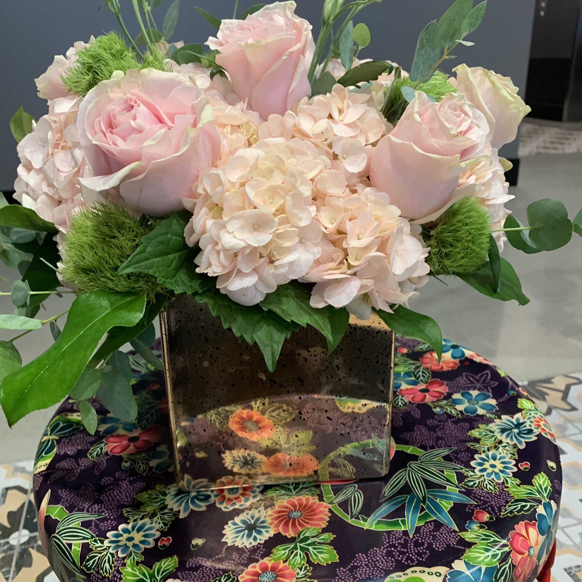 Pink roses and pale hydrangeas arranged in a square vase