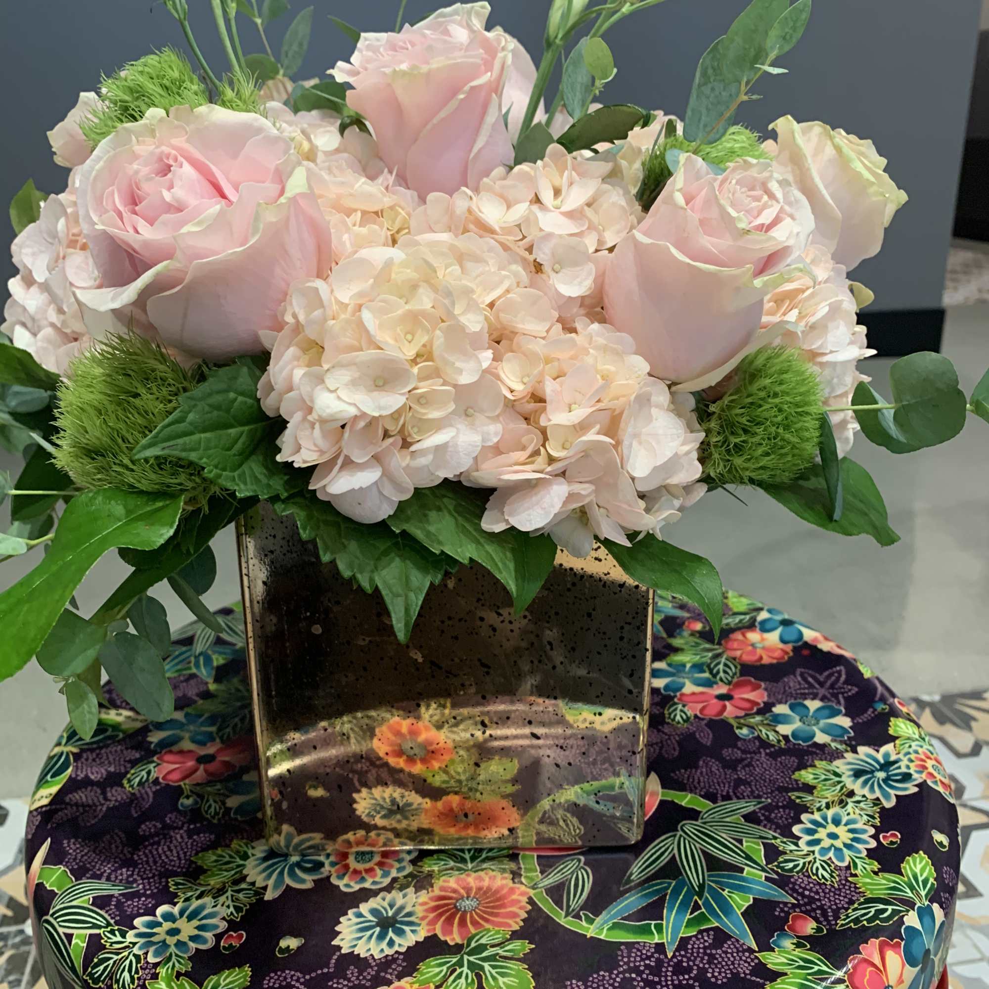 Pink roses and pale hydrangeas in a mirrored square vase