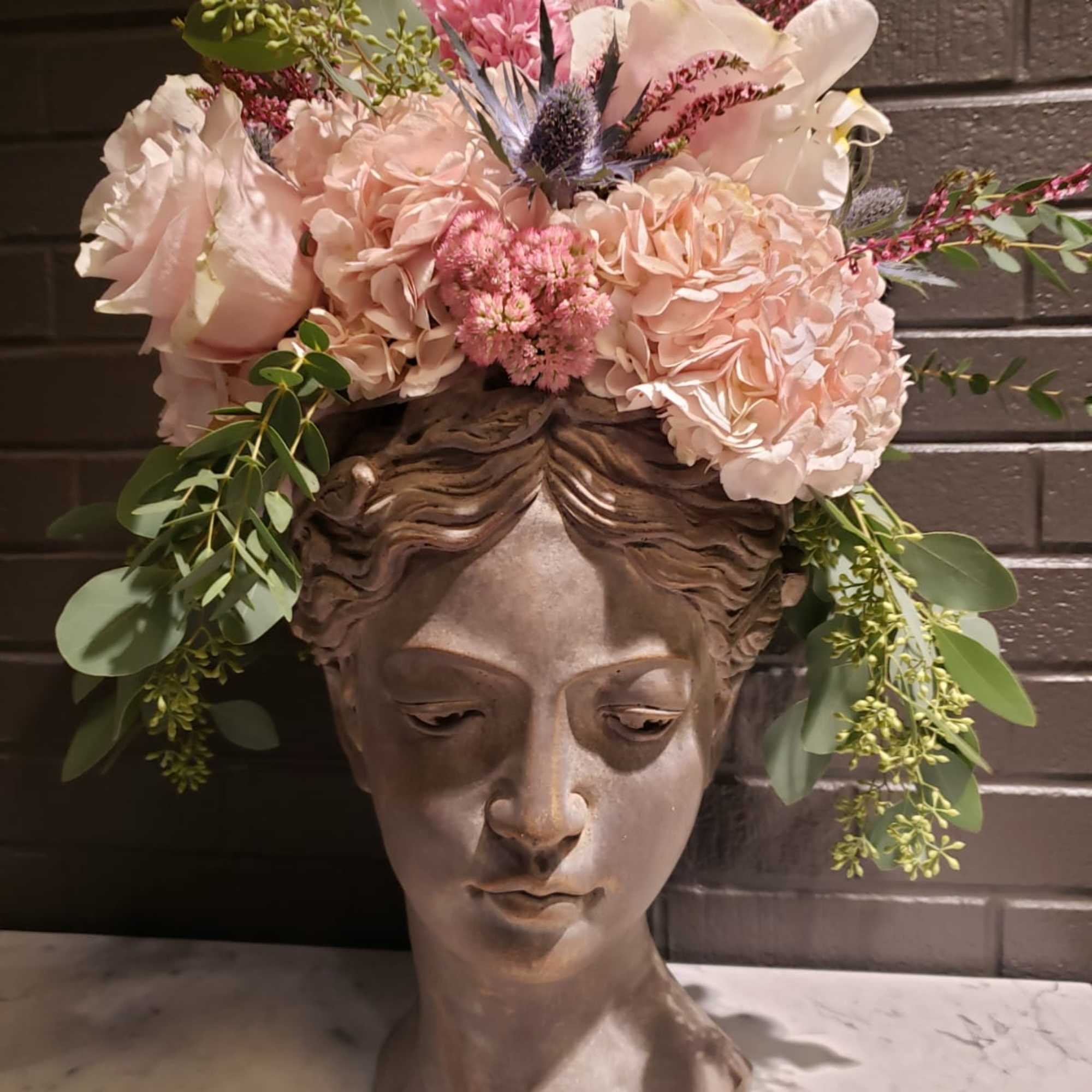 Pink floral arrangement in a sculpted bust vase