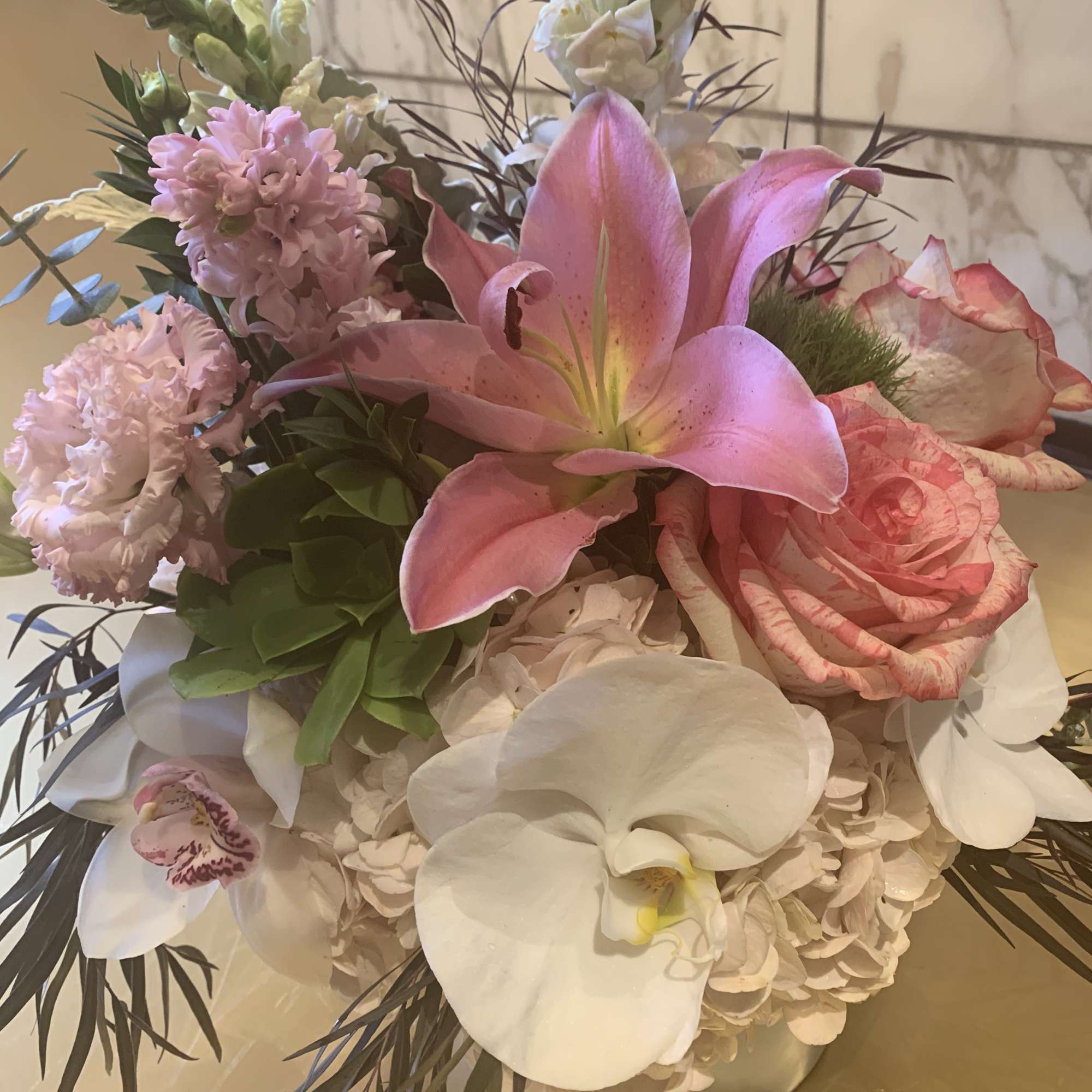Pink and white floral arrangement with lilies, roses, orchids, and hydrangeas