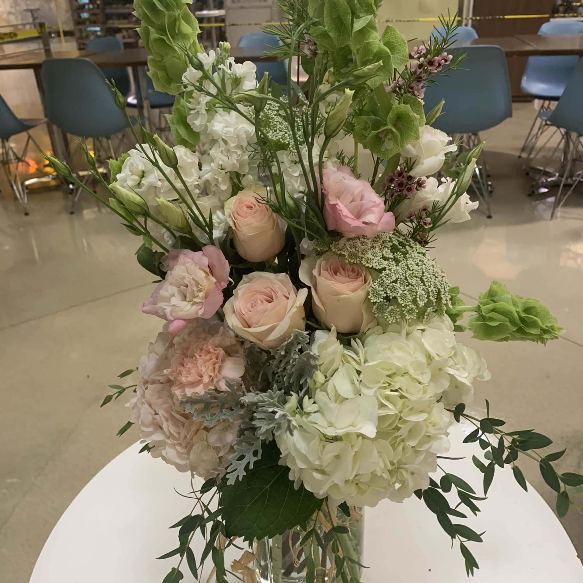 Tall bouquet of pale pink and white flowers in a glass vase