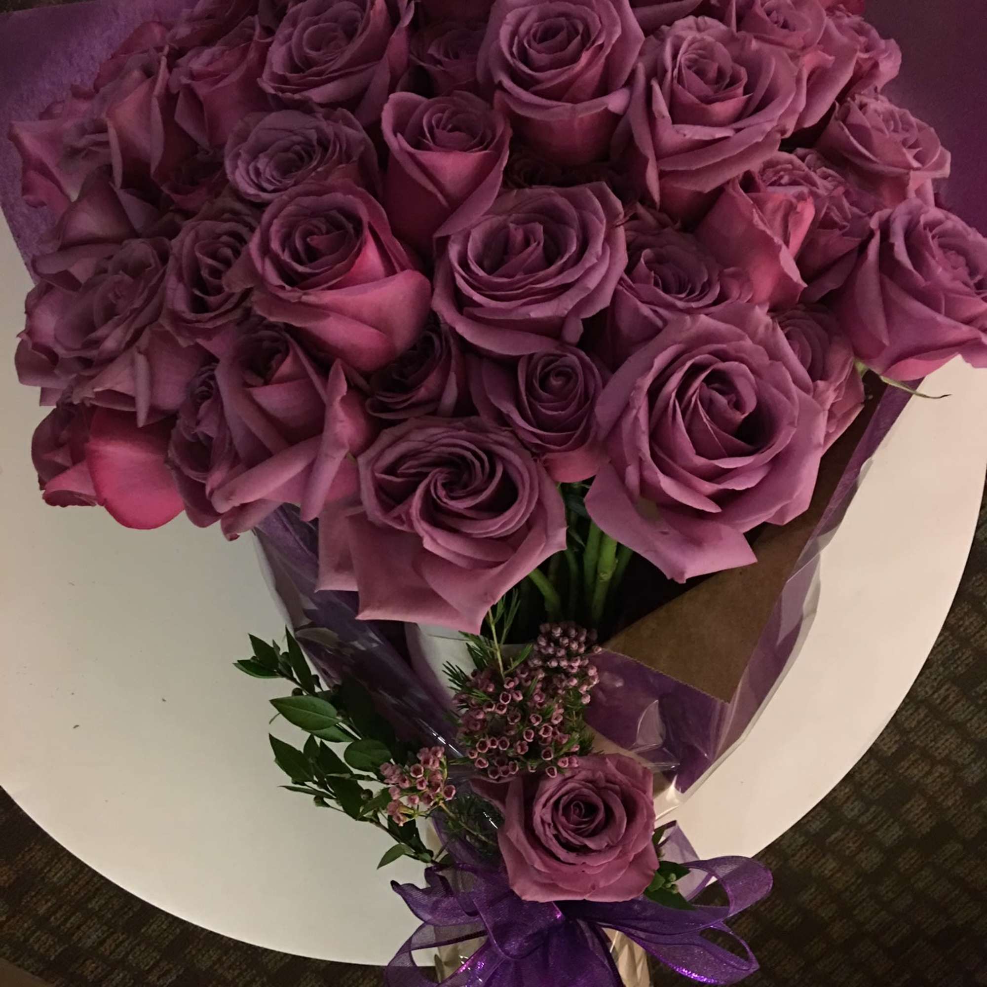 Bouquet of purple roses wrapped in purple paper with a ribbon