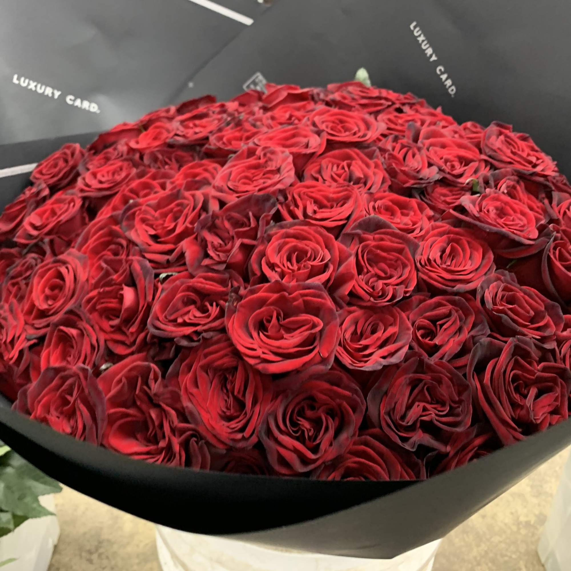 Large bouquet of red roses wrapped in black paper