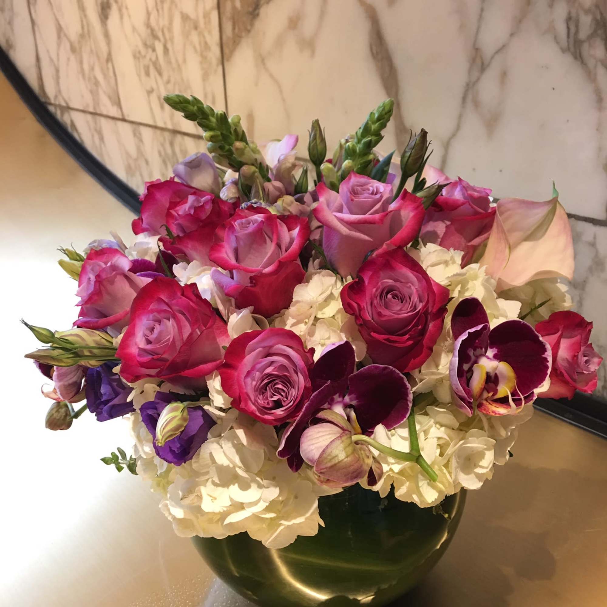 Pink and purple rose bouquet in a dark glass vase
