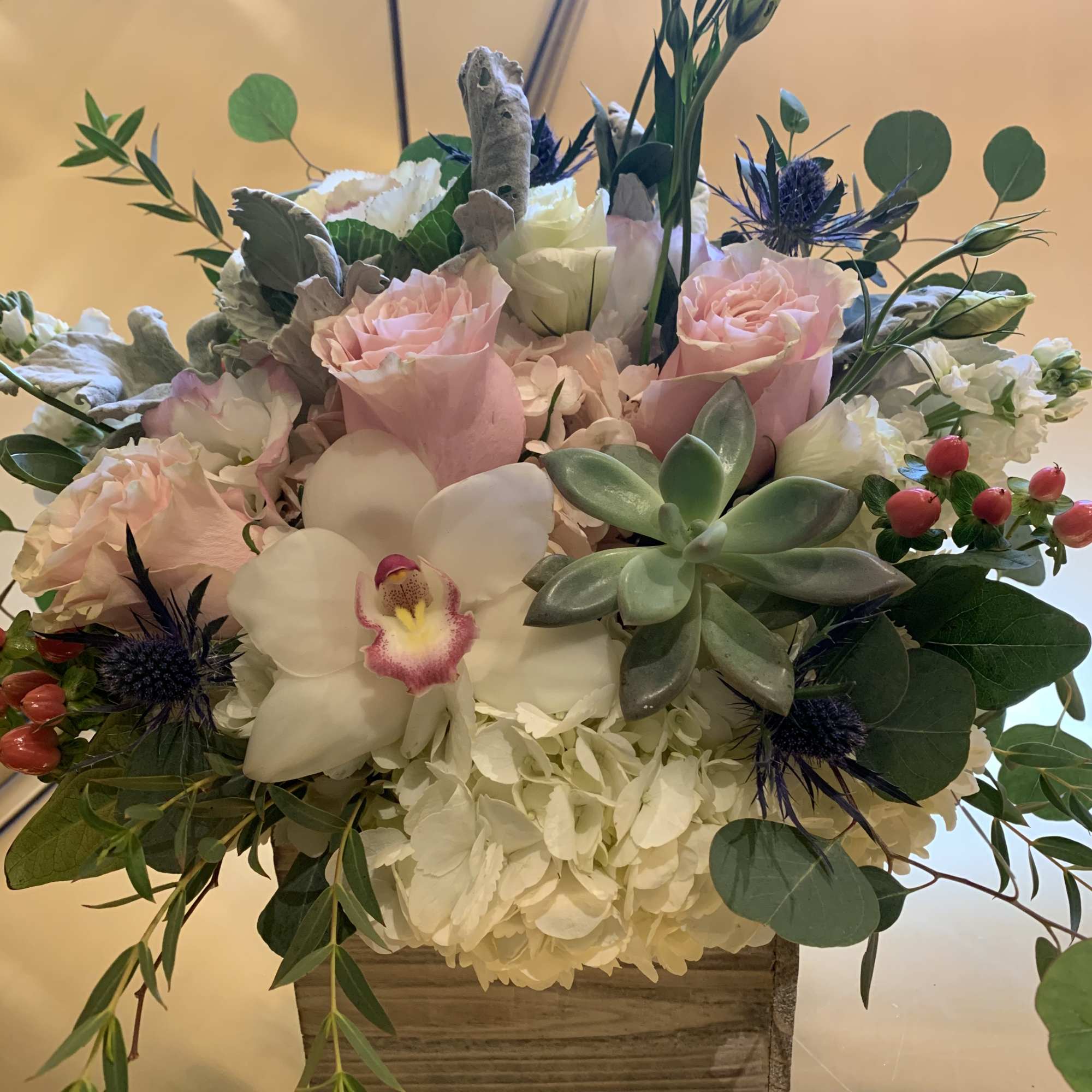 Pink roses, white orchids, and hydrangeas in a wooden box