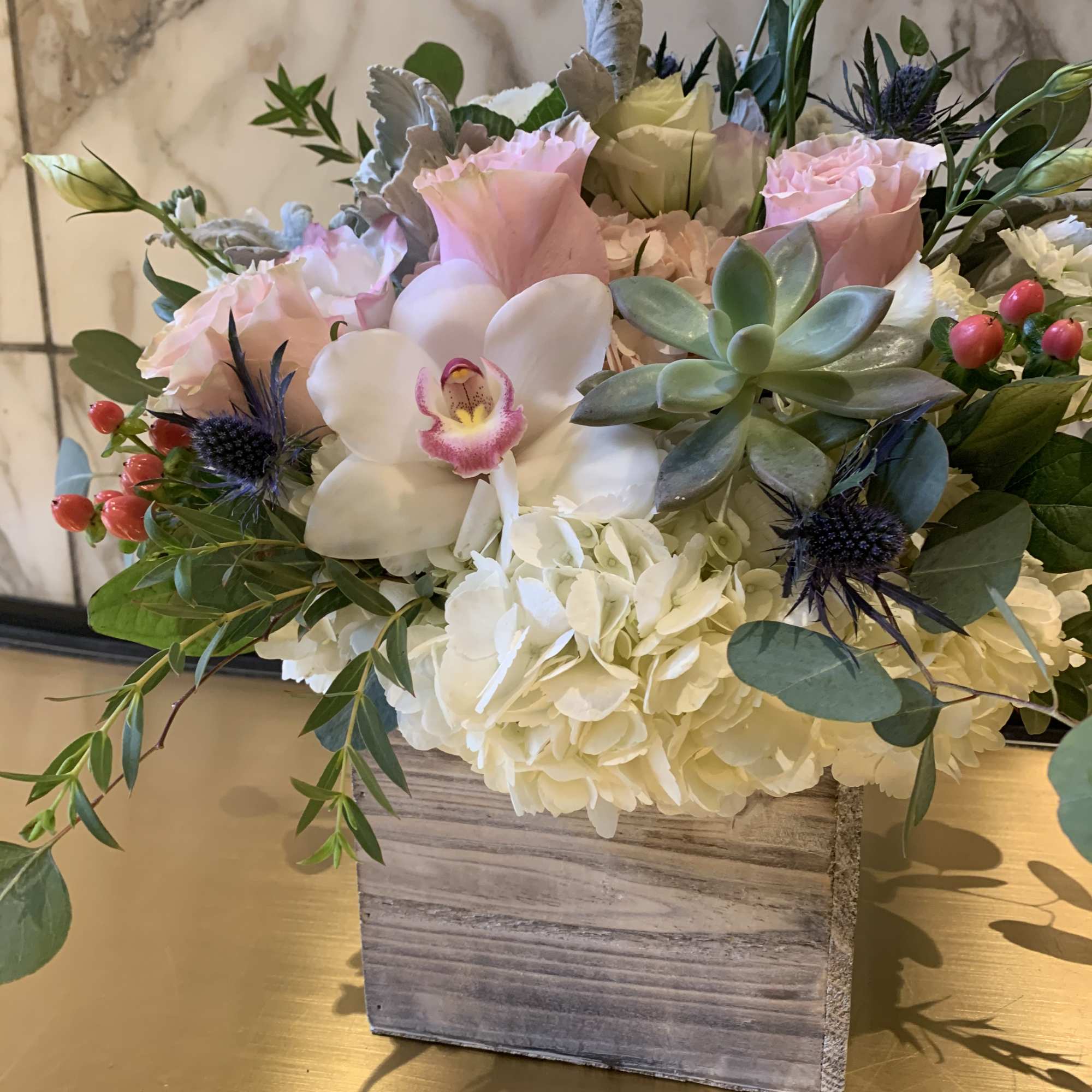Pink roses and white hydrangeas in a wooden box with a white orchid