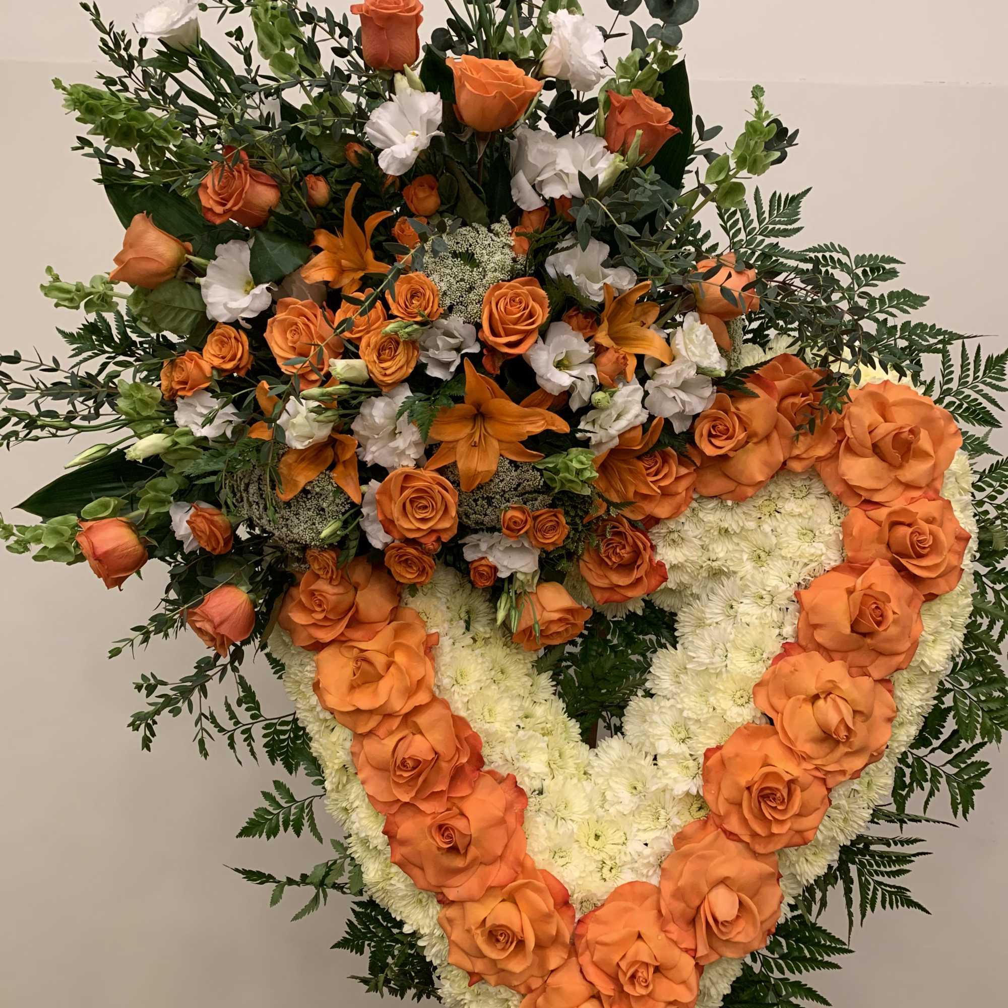 Large standing floral tribute with orange roses and white flowers
