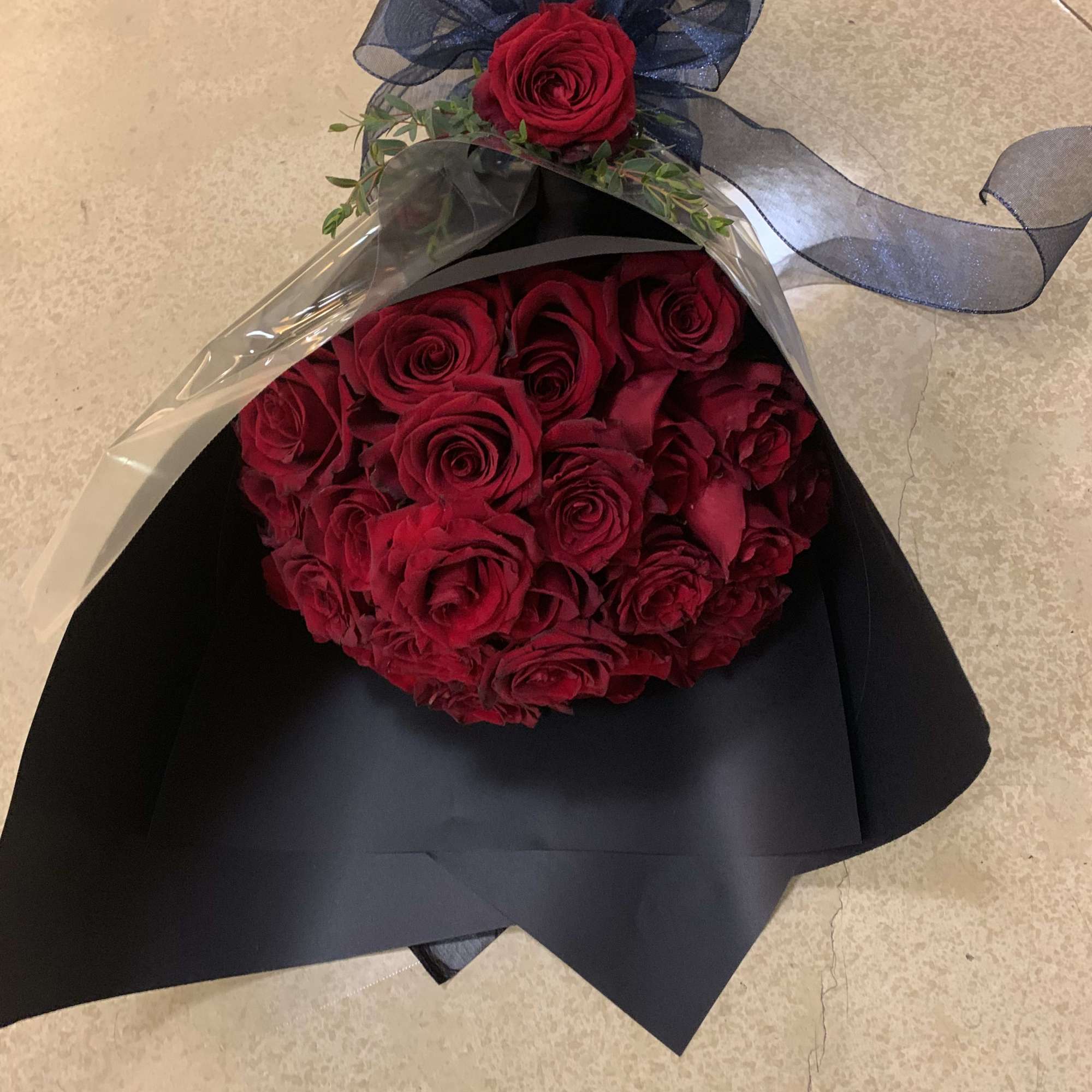 Bouquet of red roses wrapped in black paper with a dark ribbon