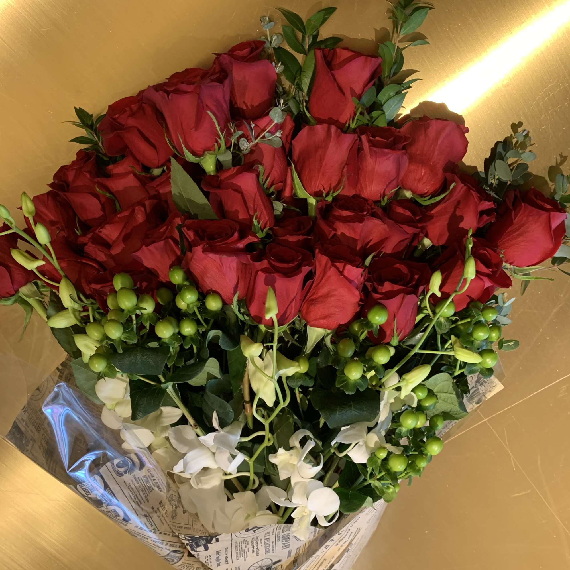 Bouquet of red roses with white orchids and green berries