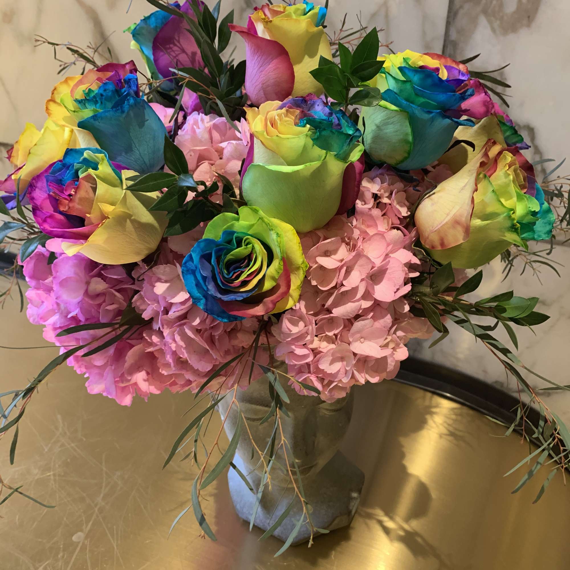 Rainbow roses in a glass vase with pink hydrangeas