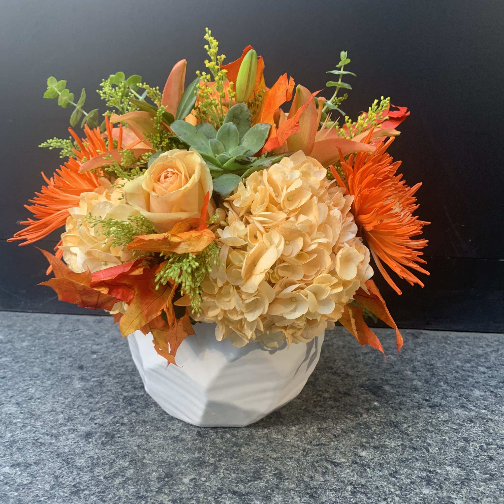 Orange and cream floral arrangement in a white vase
