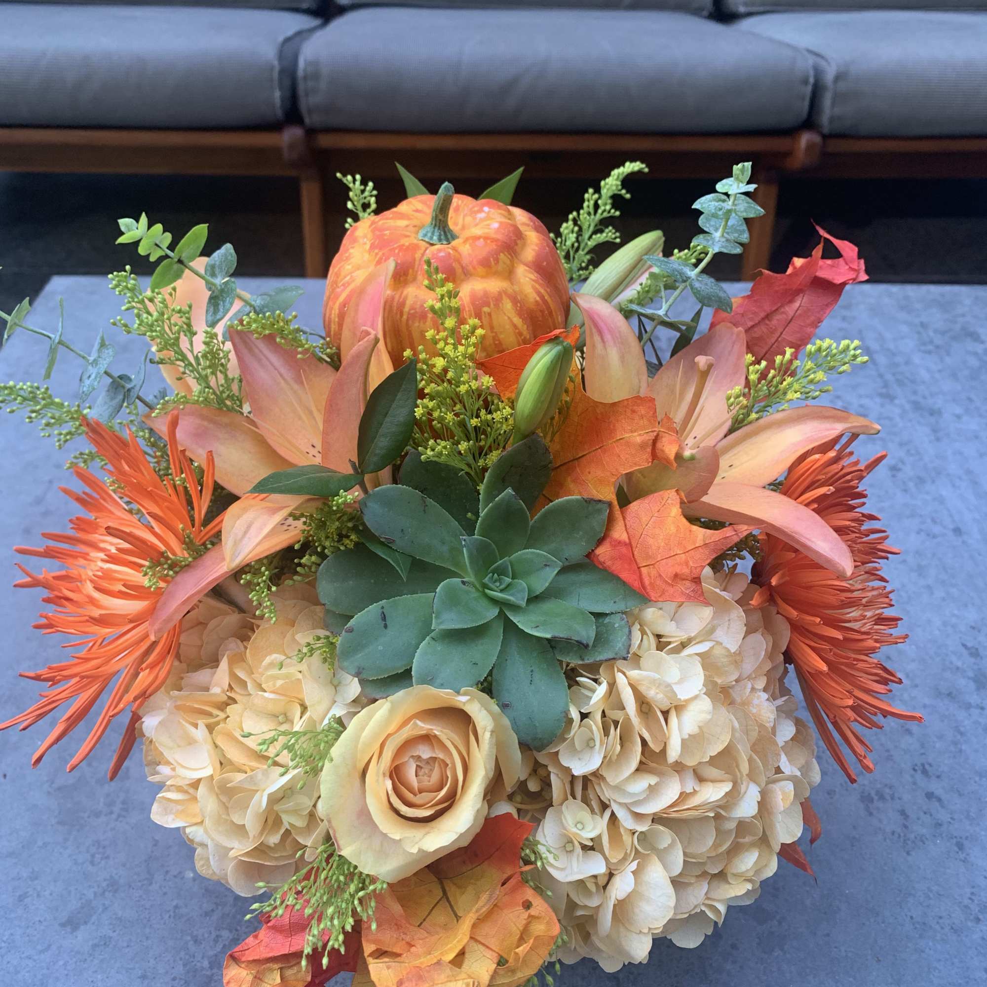 Autumn bouquet with orange flowers, cream hydrangeas, and a small pumpkin