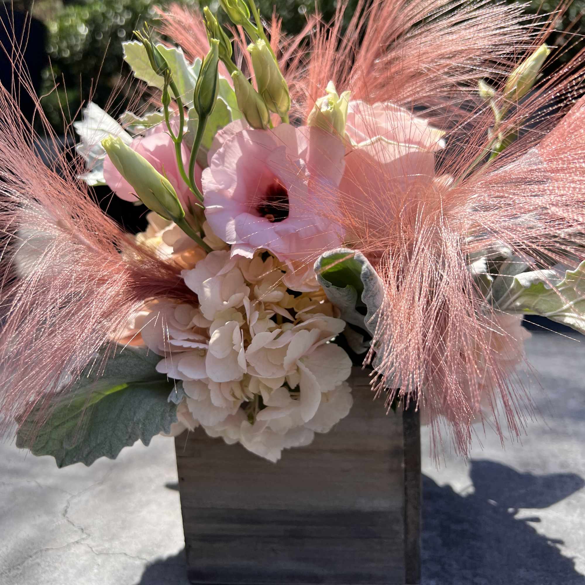 Pink and cream floral arrangement in a dark wooden box