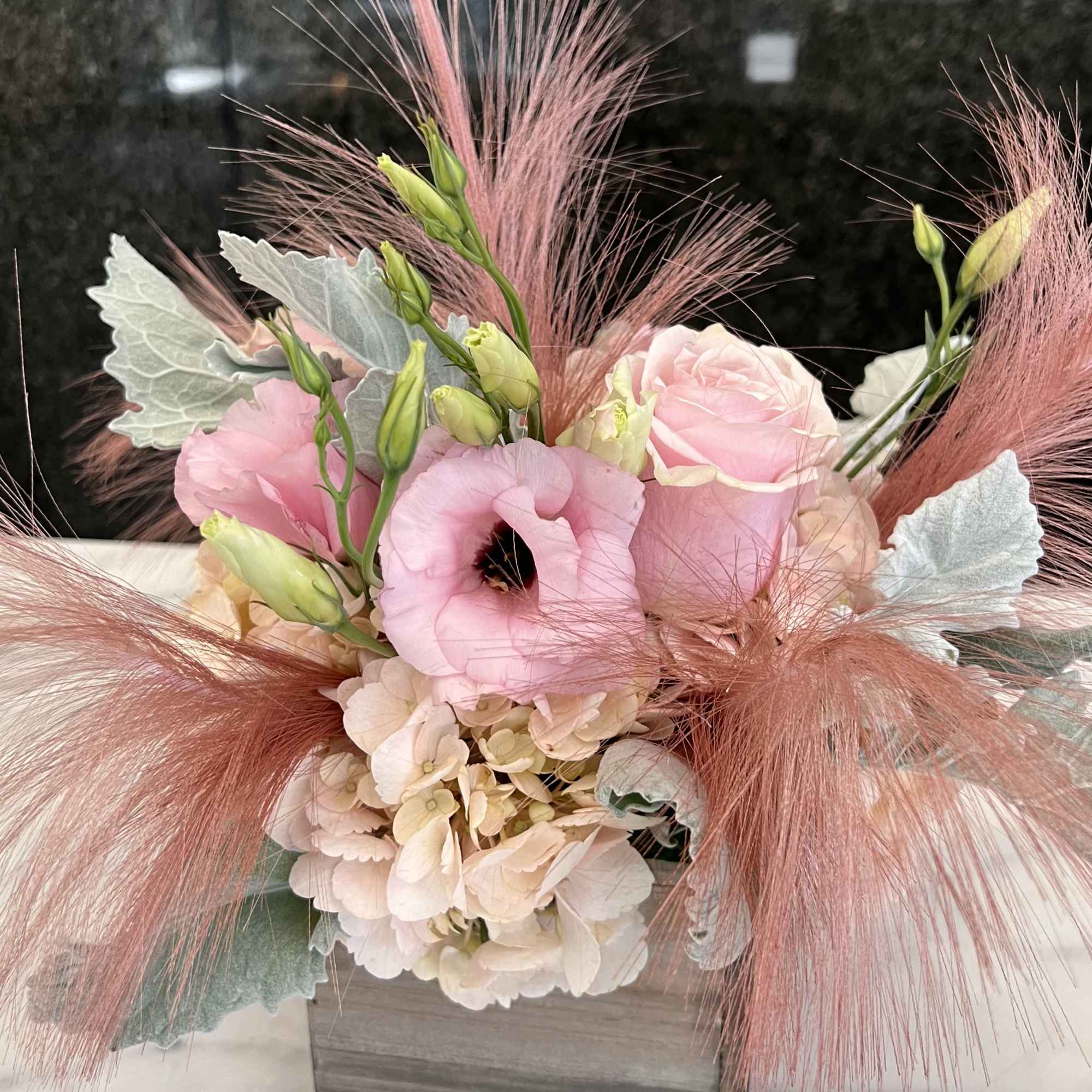 Pink and cream floral arrangement in a wooden box with feathery accents