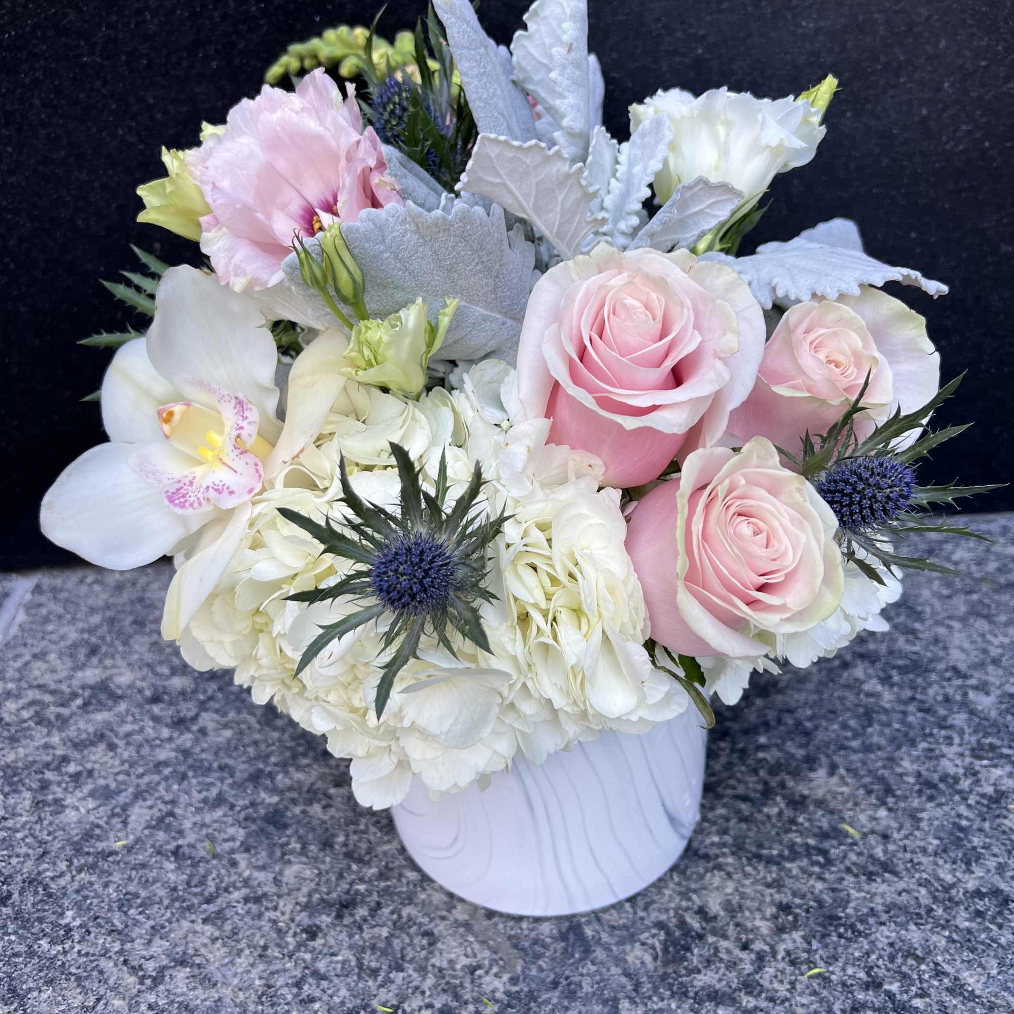 Pink roses and white blooms arranged in a white vase