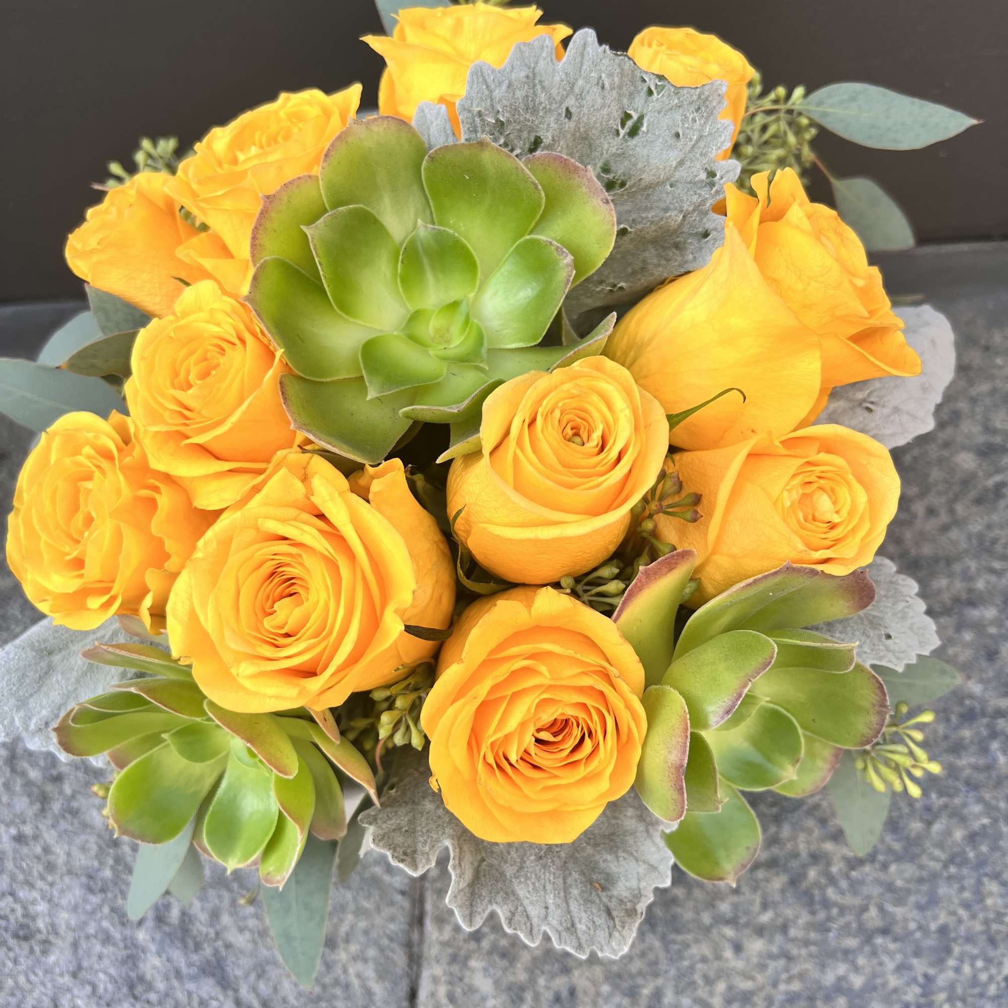 Bouquet of yellow roses with green succulents and silver foliage