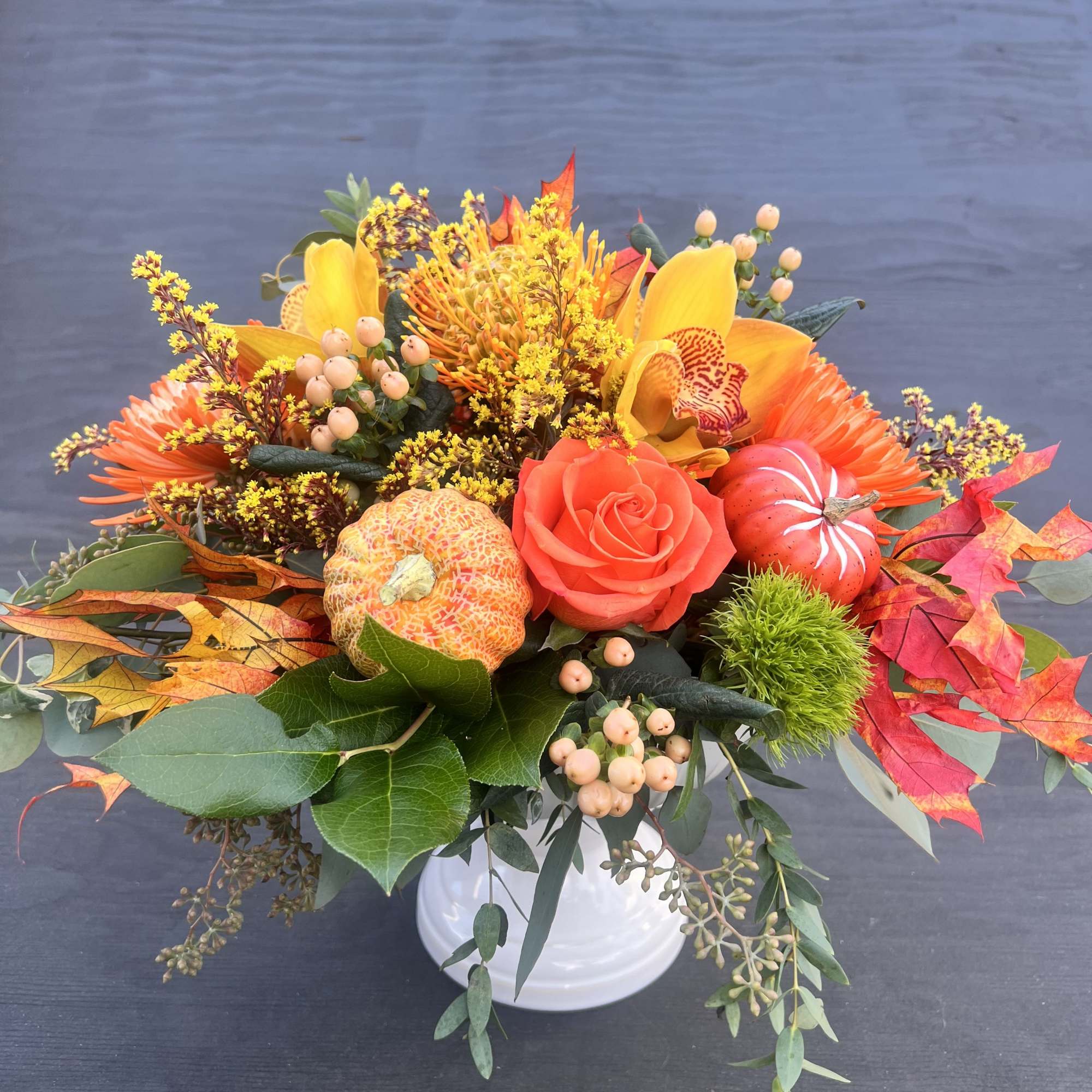 Autumn floral arrangement in a white vase with orange and yellow blooms