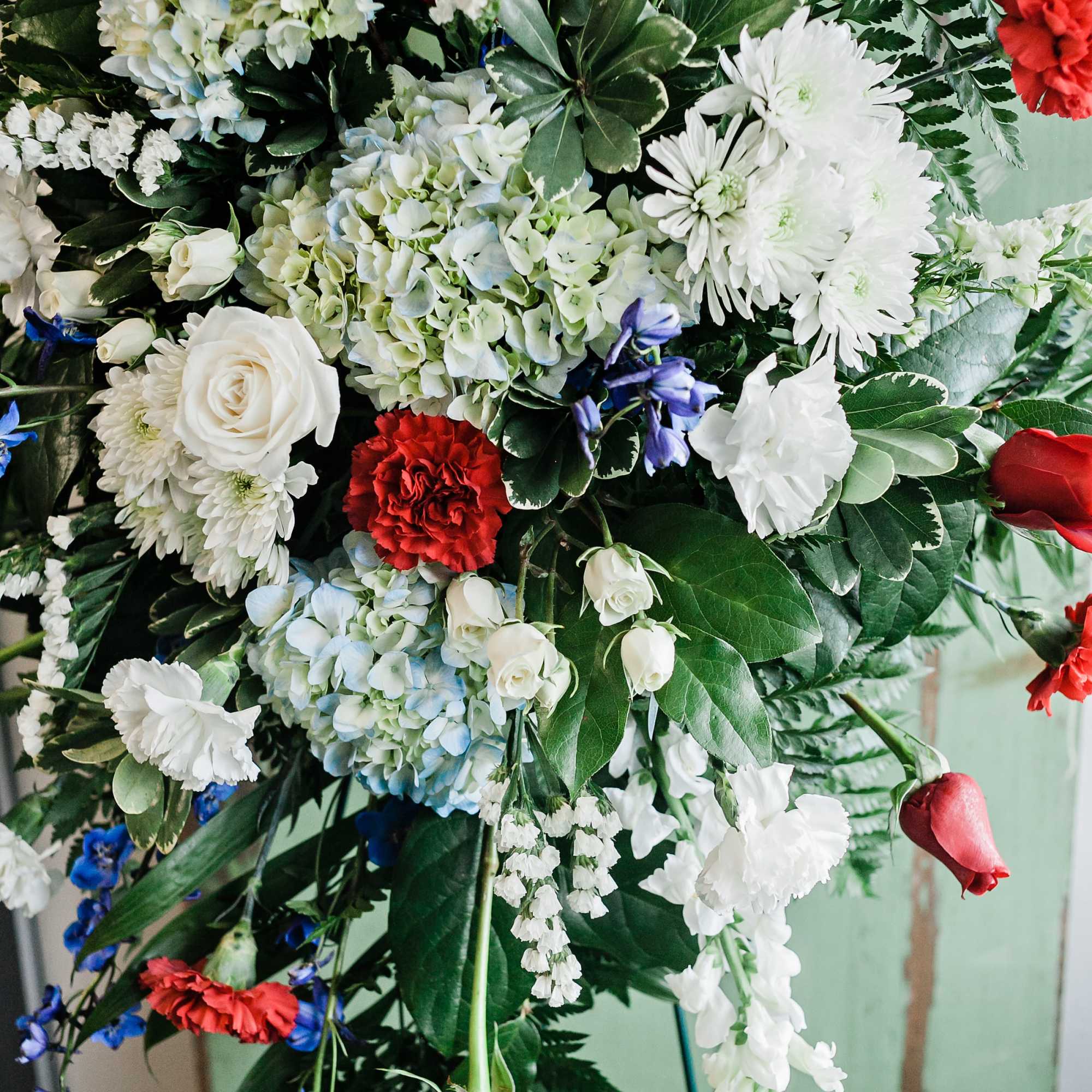 Large standing floral spray with white, red, and blue flowers
