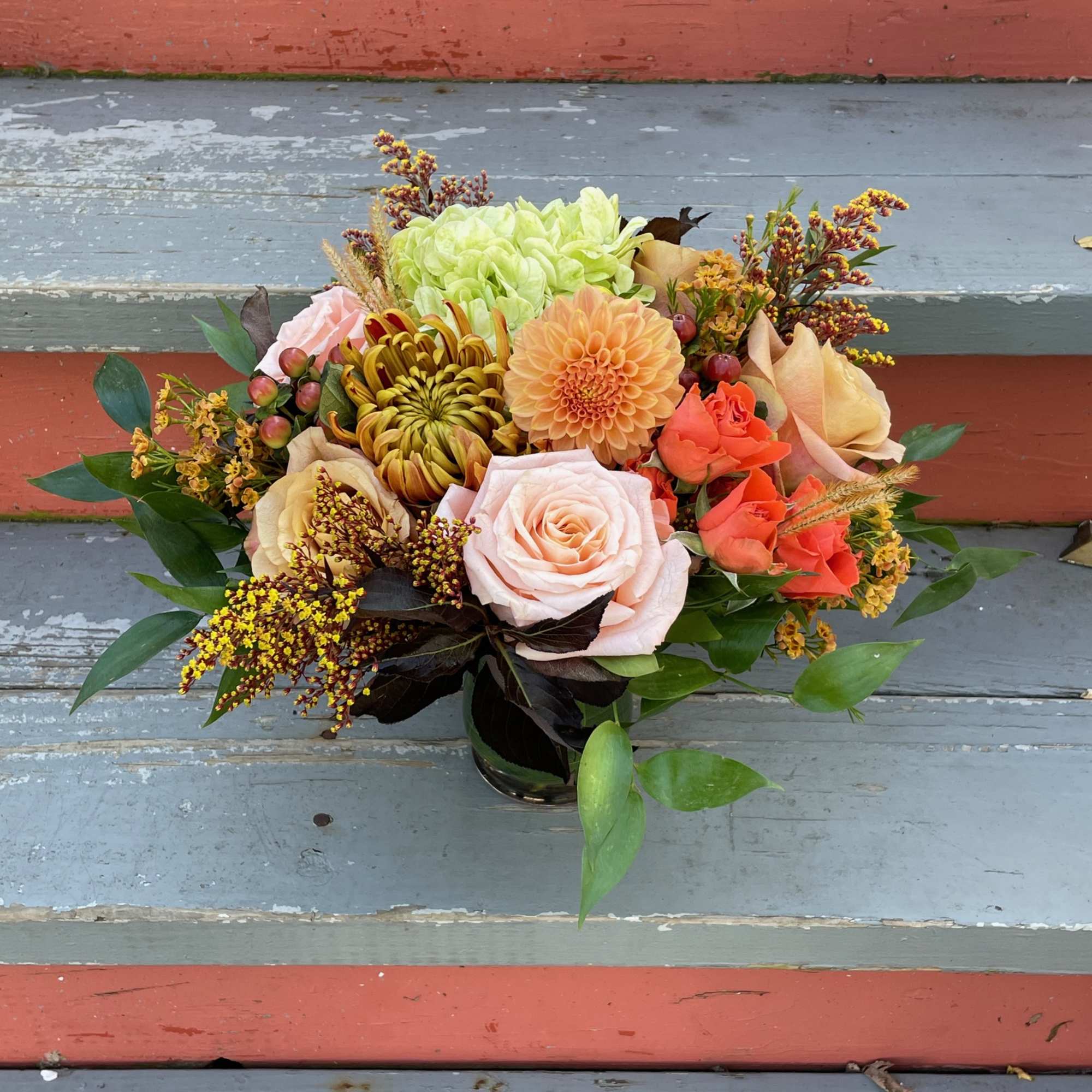 Mixed bouquet of roses, dahlias, and chrysanthemums in a glass vase