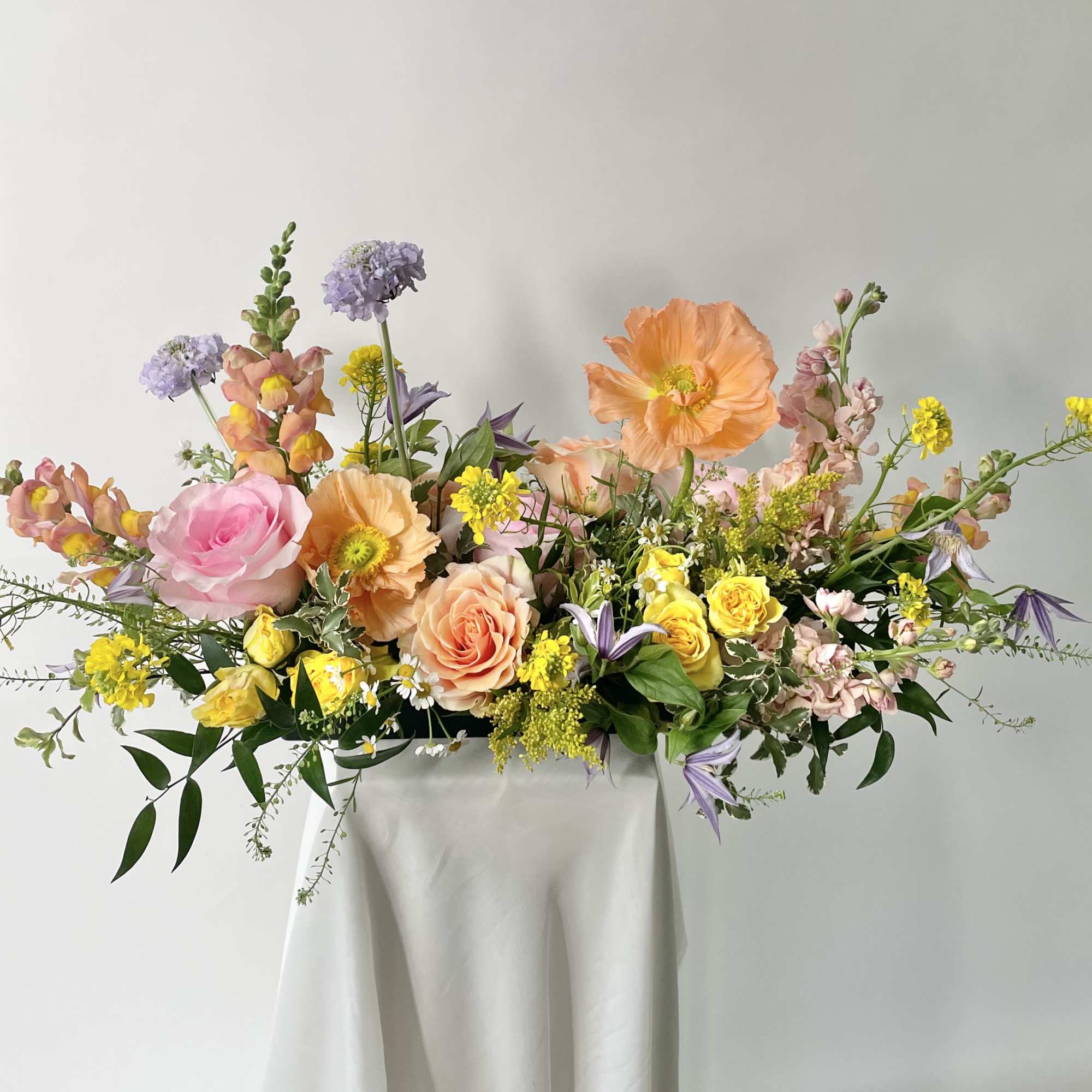 Mixed pastel flower arrangement on a draped pedestal
