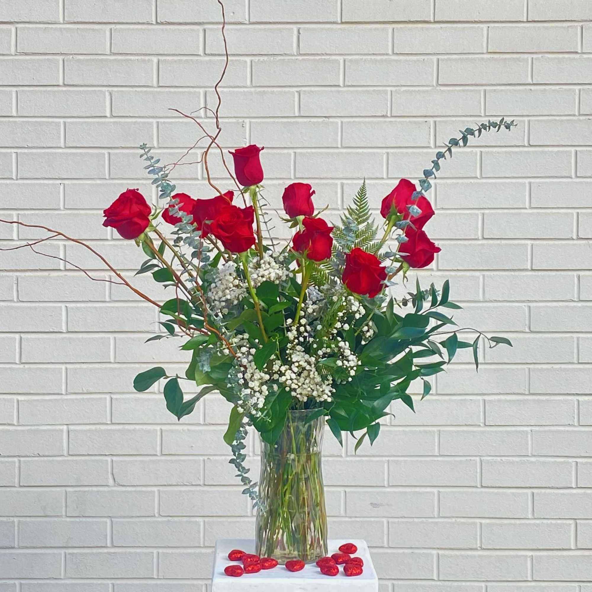 Tall vase arrangement of red roses with white filler flowers