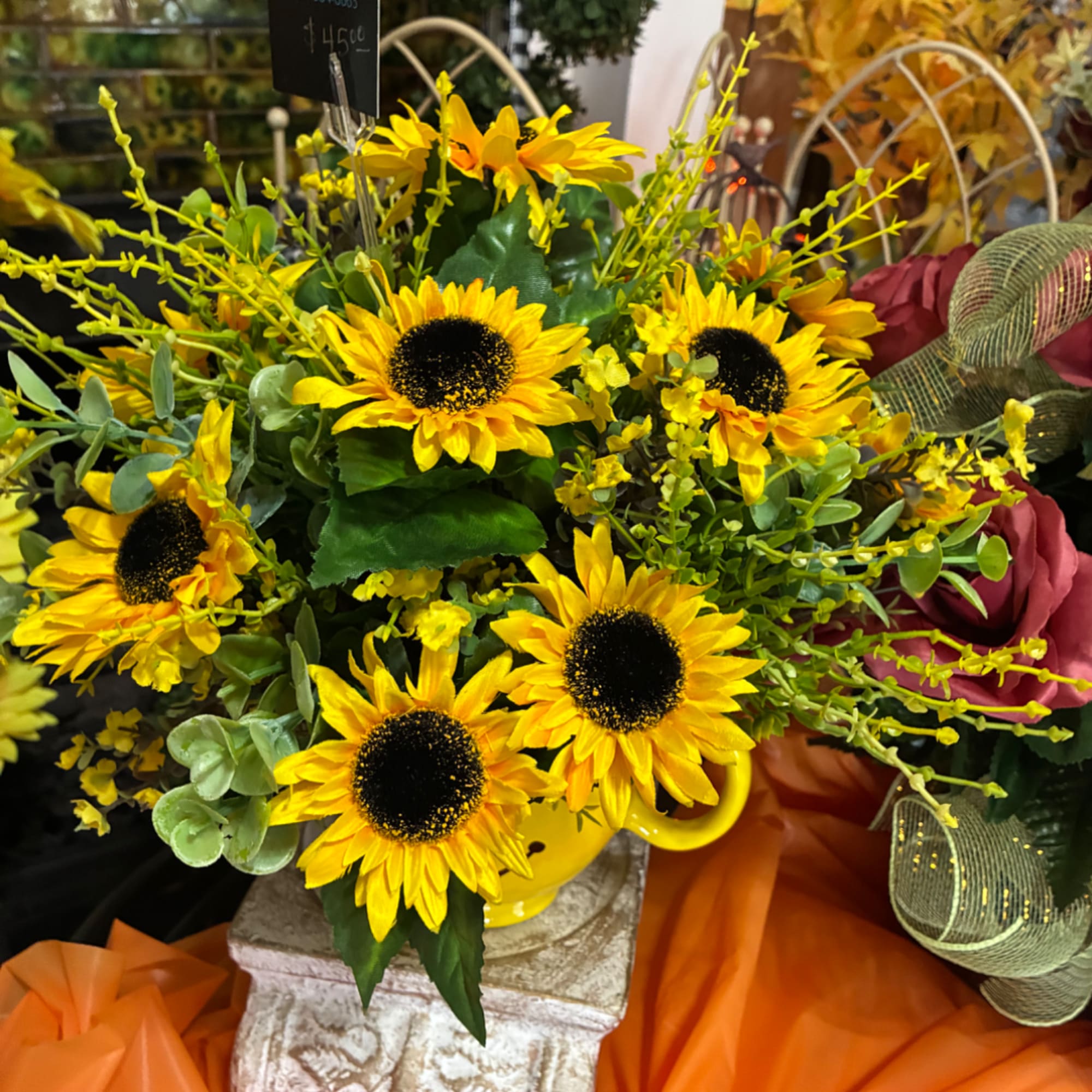 Yellow sunflowers arranged in a yellow vase with mixed greenery