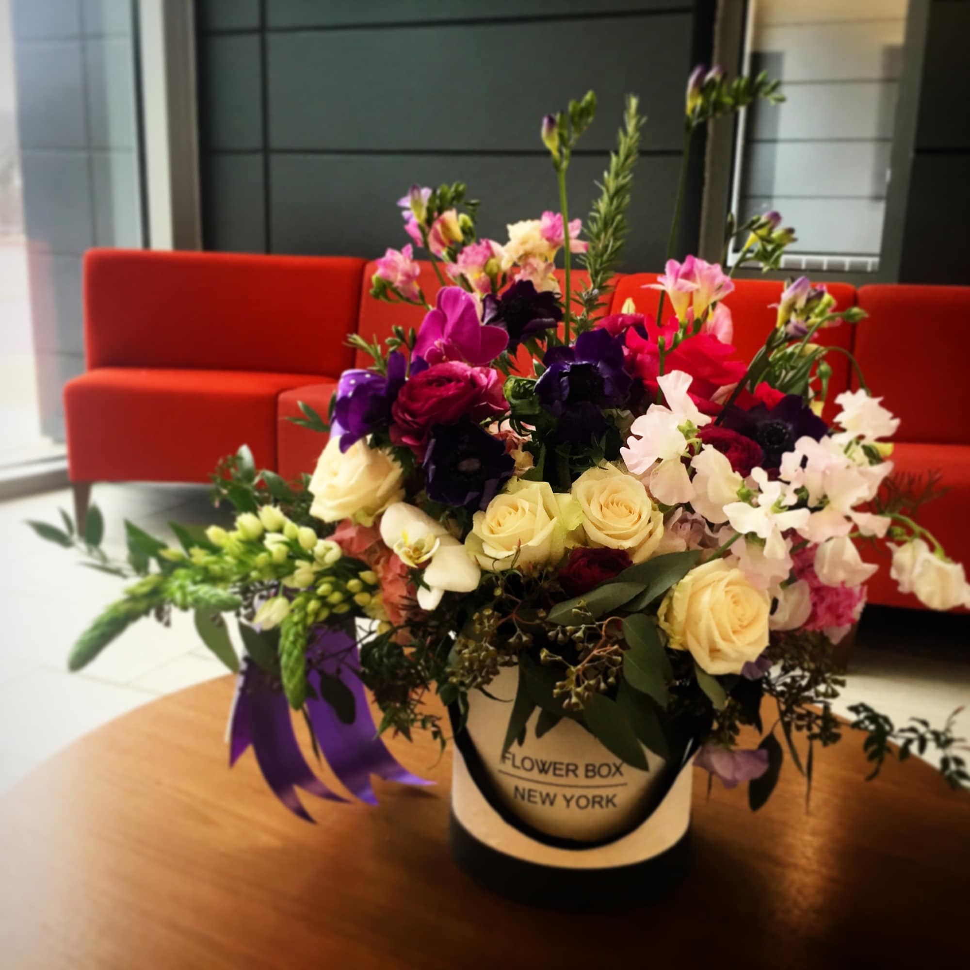 Mixed bouquet of roses and orchids in a round gift box