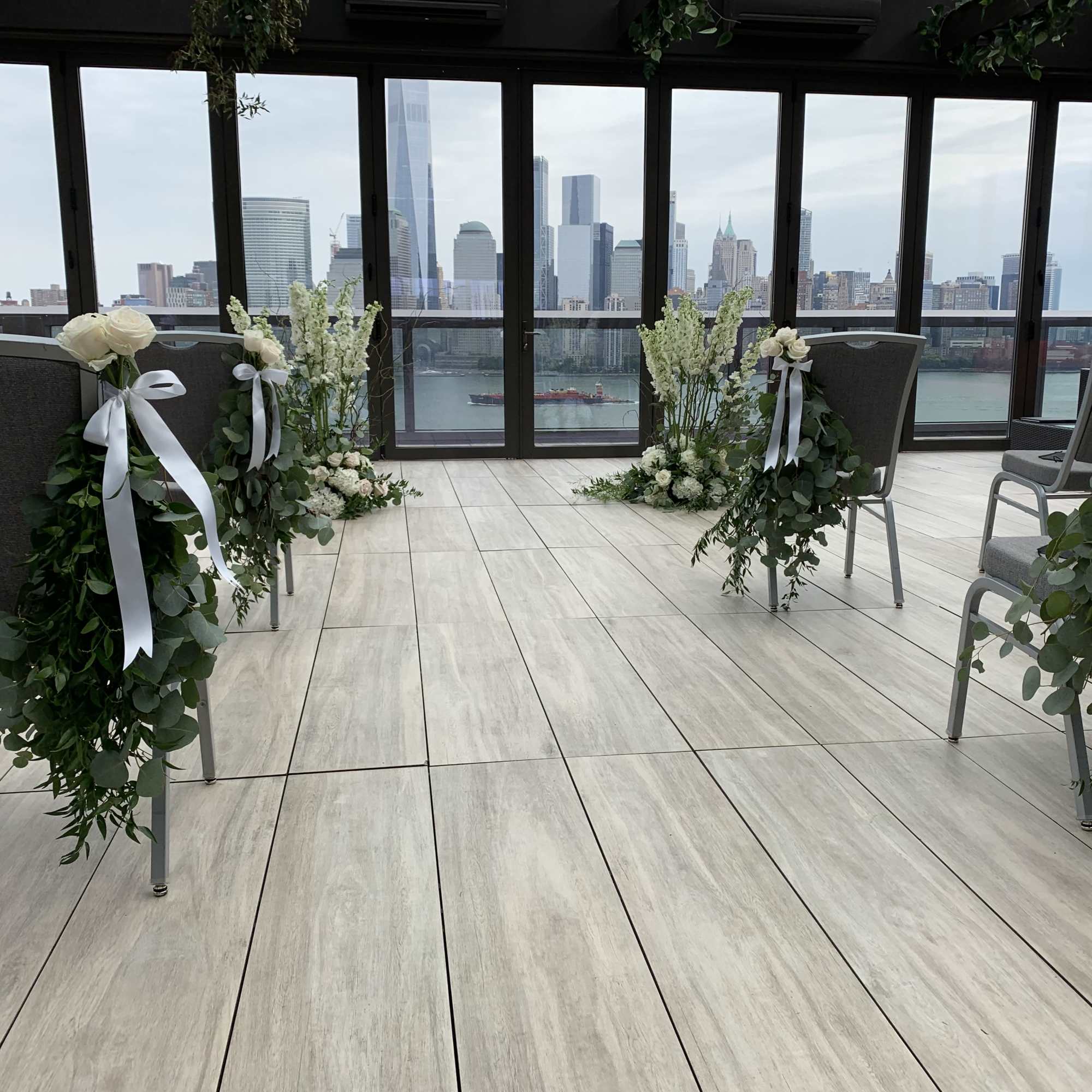 White floral chair decorations with ribbons in a bright room overlooking the city