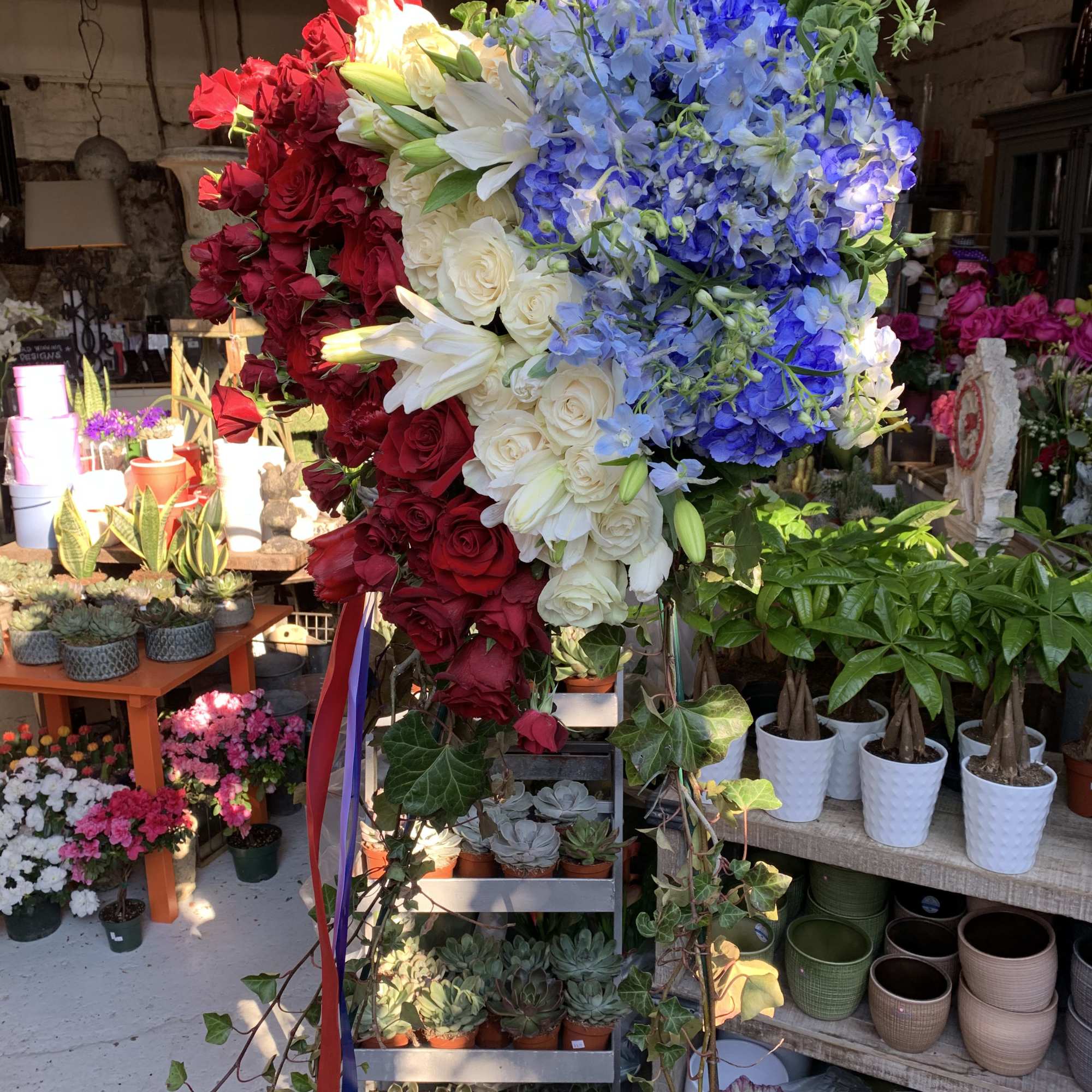 Large floral heart with red, white, and blue flowers on a stand