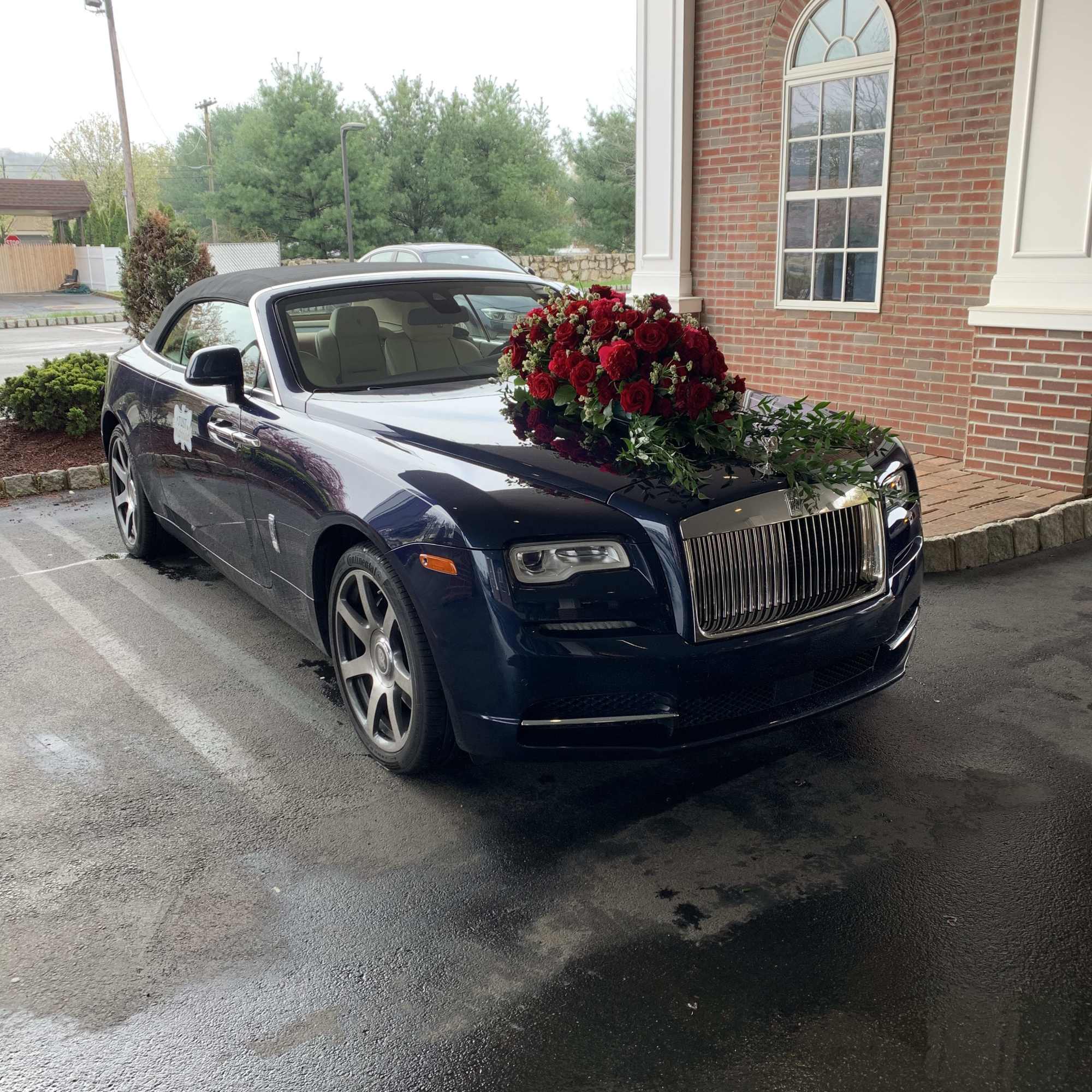 Red rose arrangement on the hood of a dark luxury car