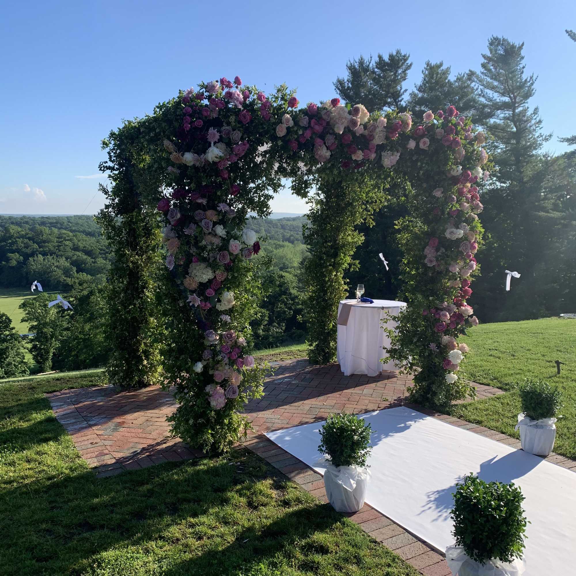 Floral-covered wedding arch with pink and white roses outdoors