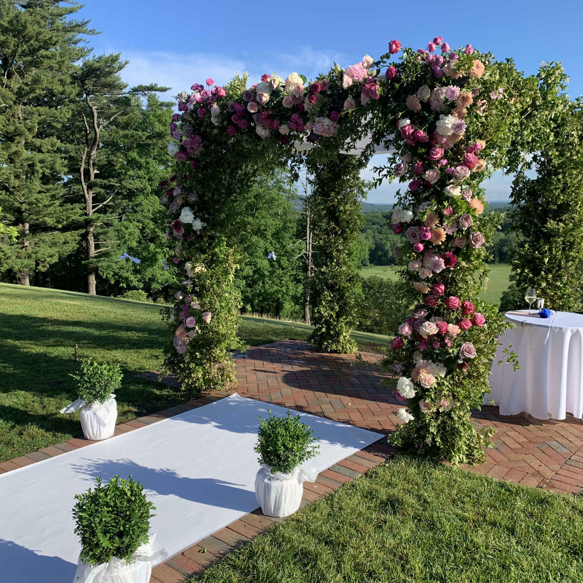 Floral wedding arch covered in pink and white roses outdoors, photo 4 of 5
