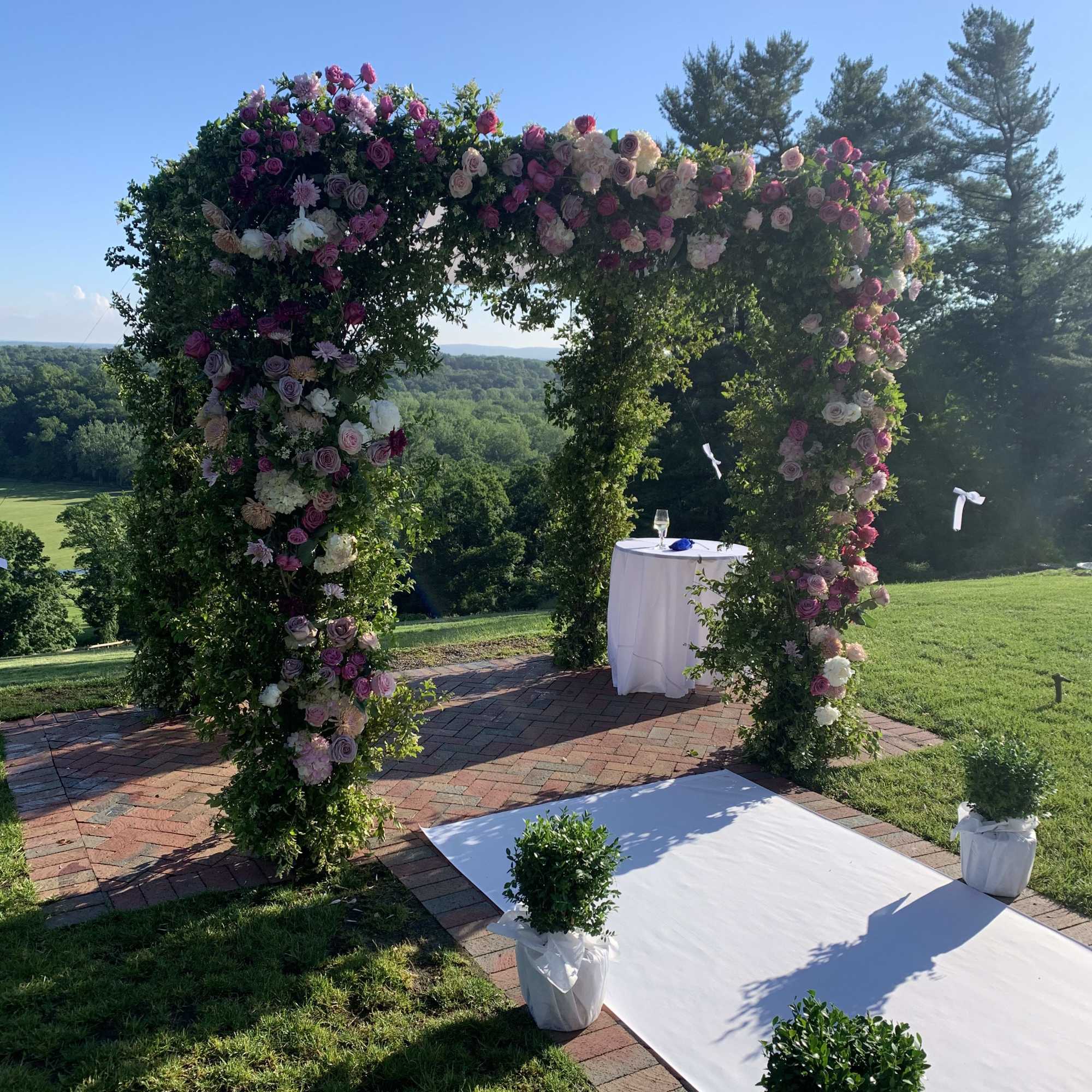 Floral wedding arch covered in pink and white roses outdoors, photo 5 of 5
