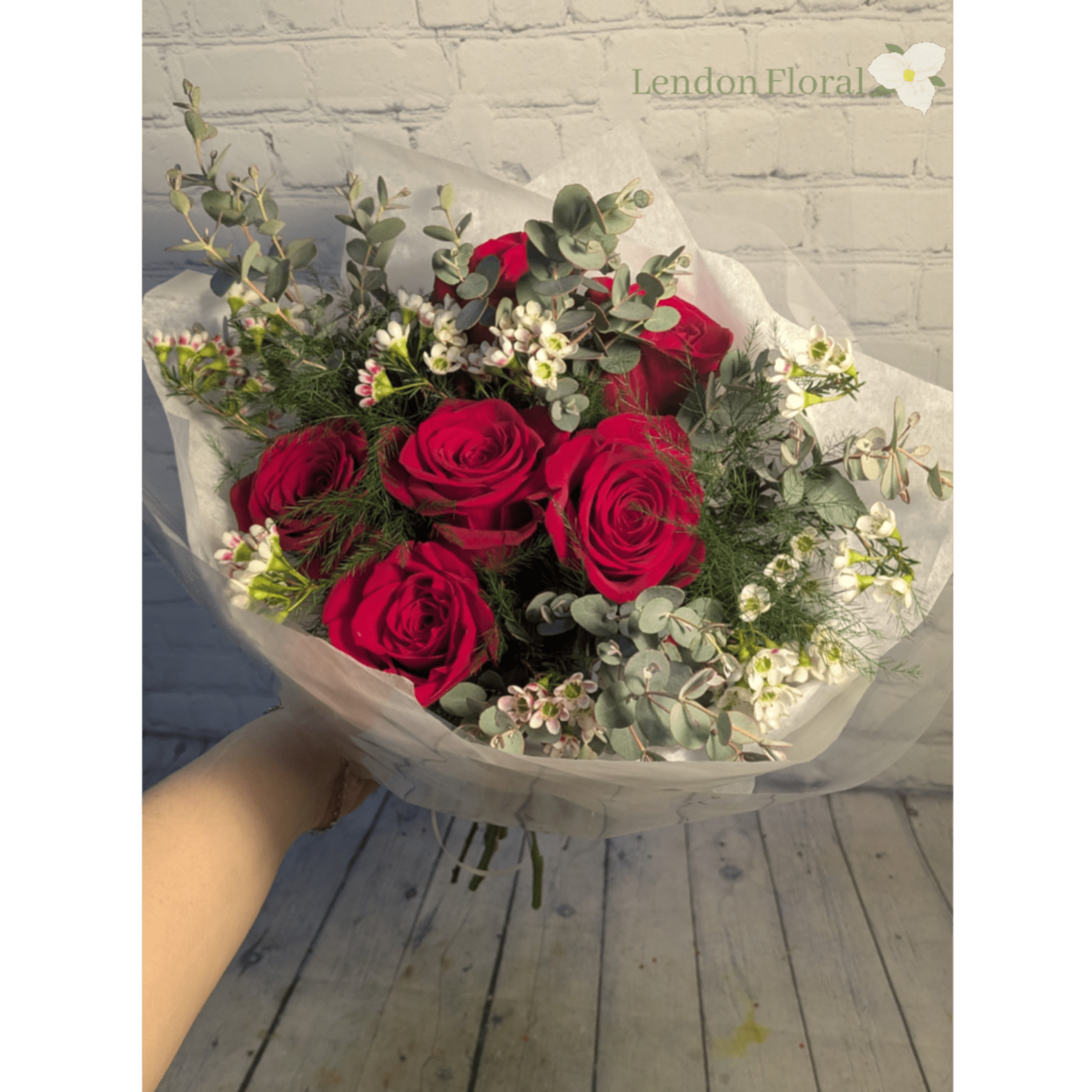 Bouquet of red roses with white filler flowers and eucalyptus in white wrap