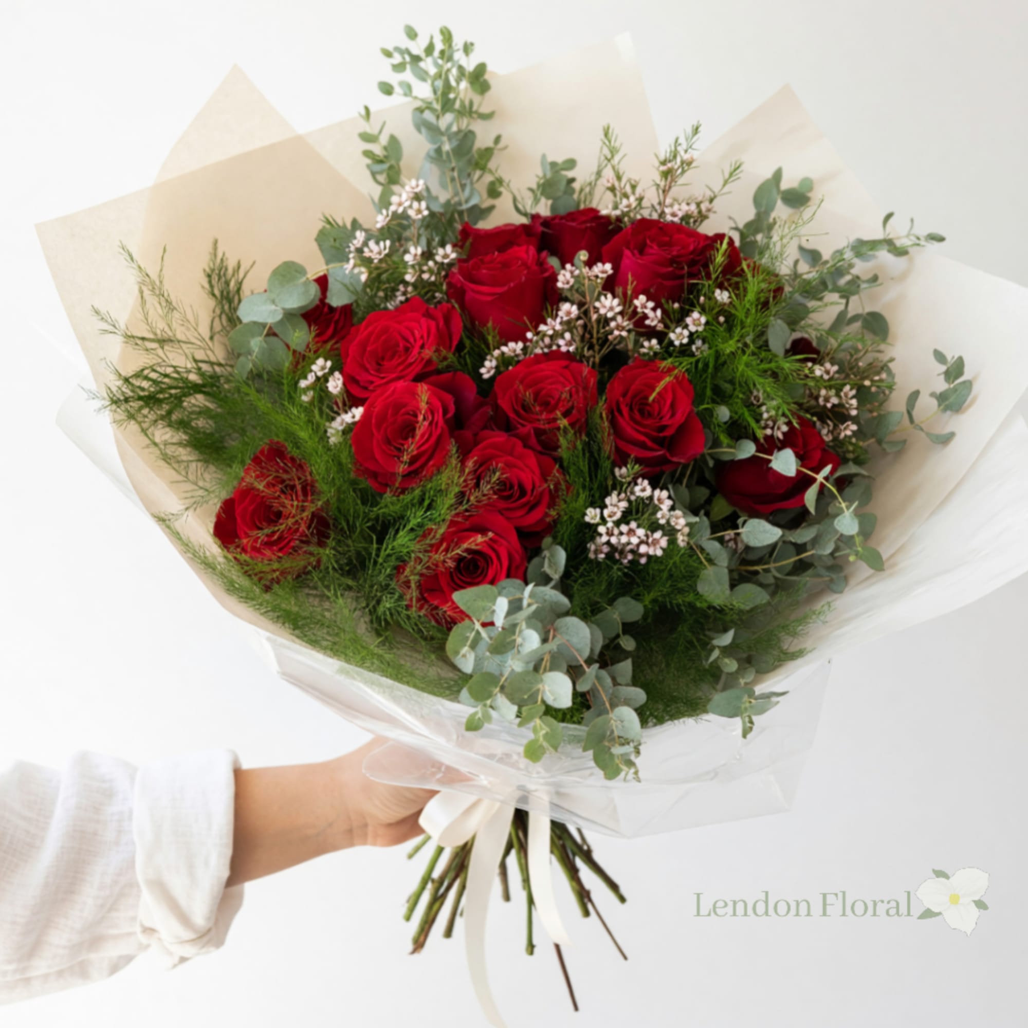 Handheld bouquet of red roses with airy greenery and white filler flowers