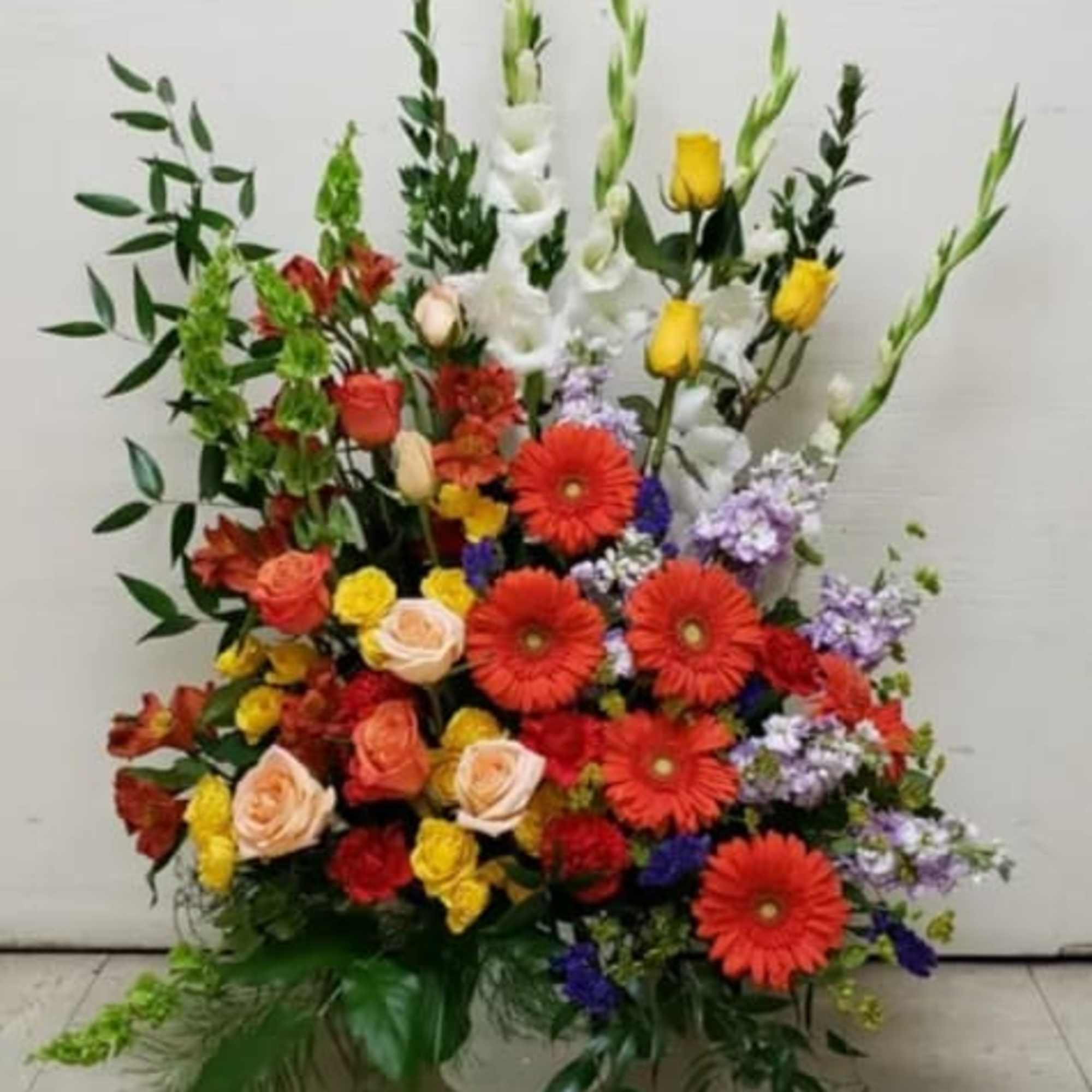 Large mixed flower arrangement with red gerberas, roses, and white gladiolus