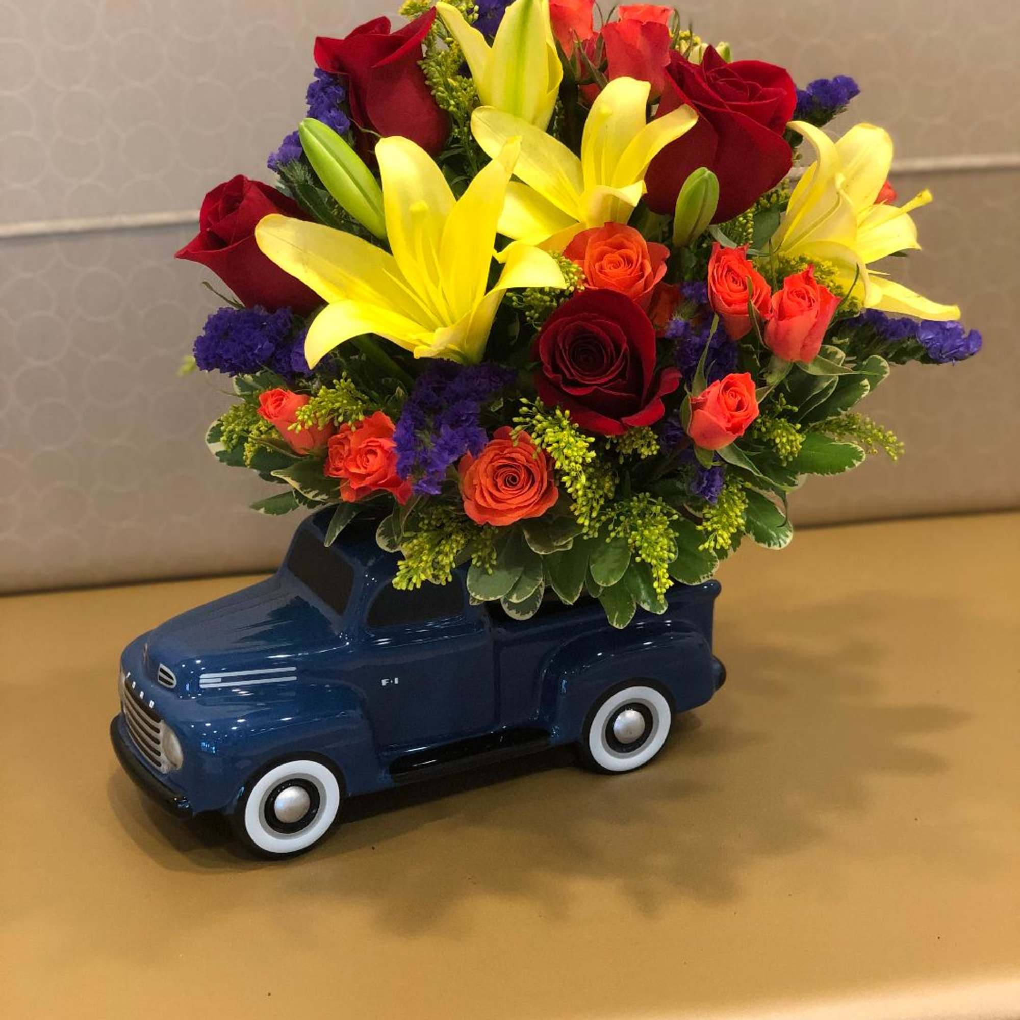 Bouquet of red roses and yellow lilies in a blue toy truck