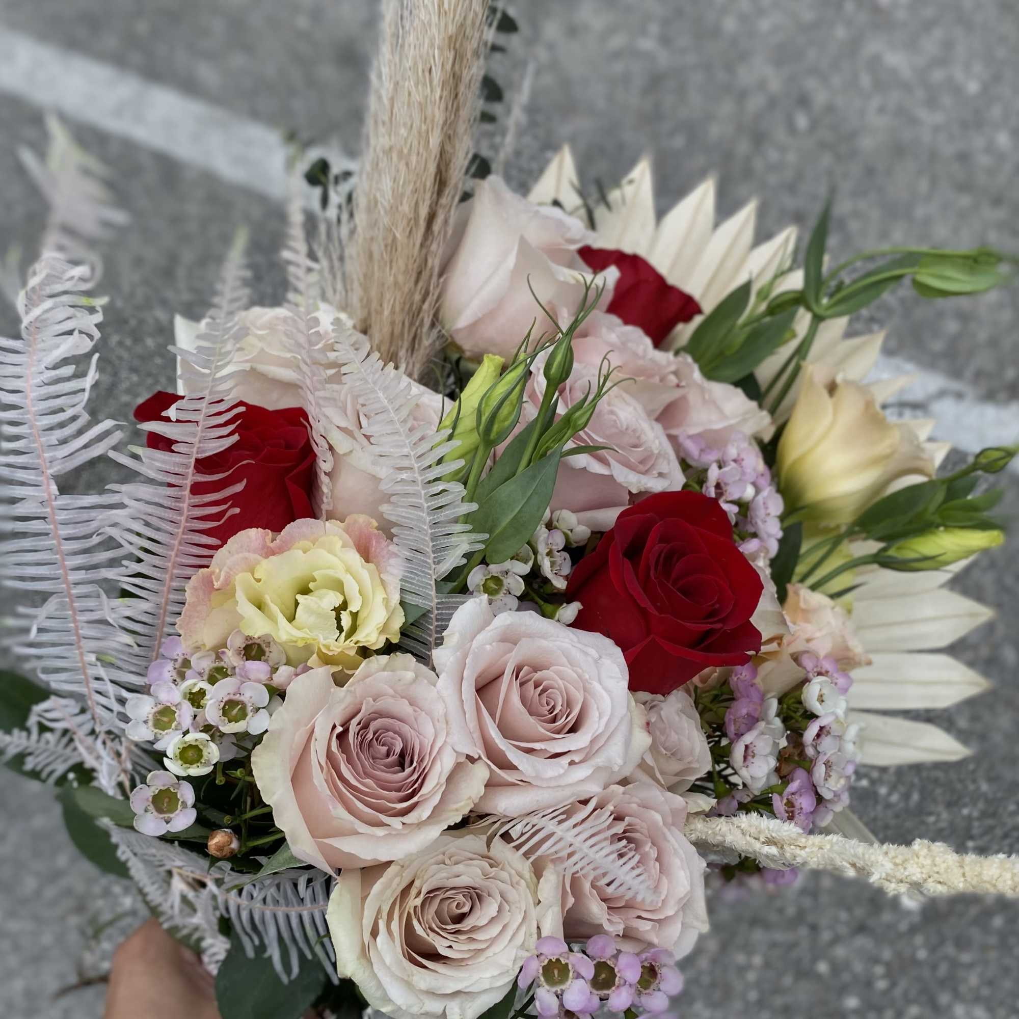Hand-tied bouquet of pale pink and red roses with small lavender filler flowers