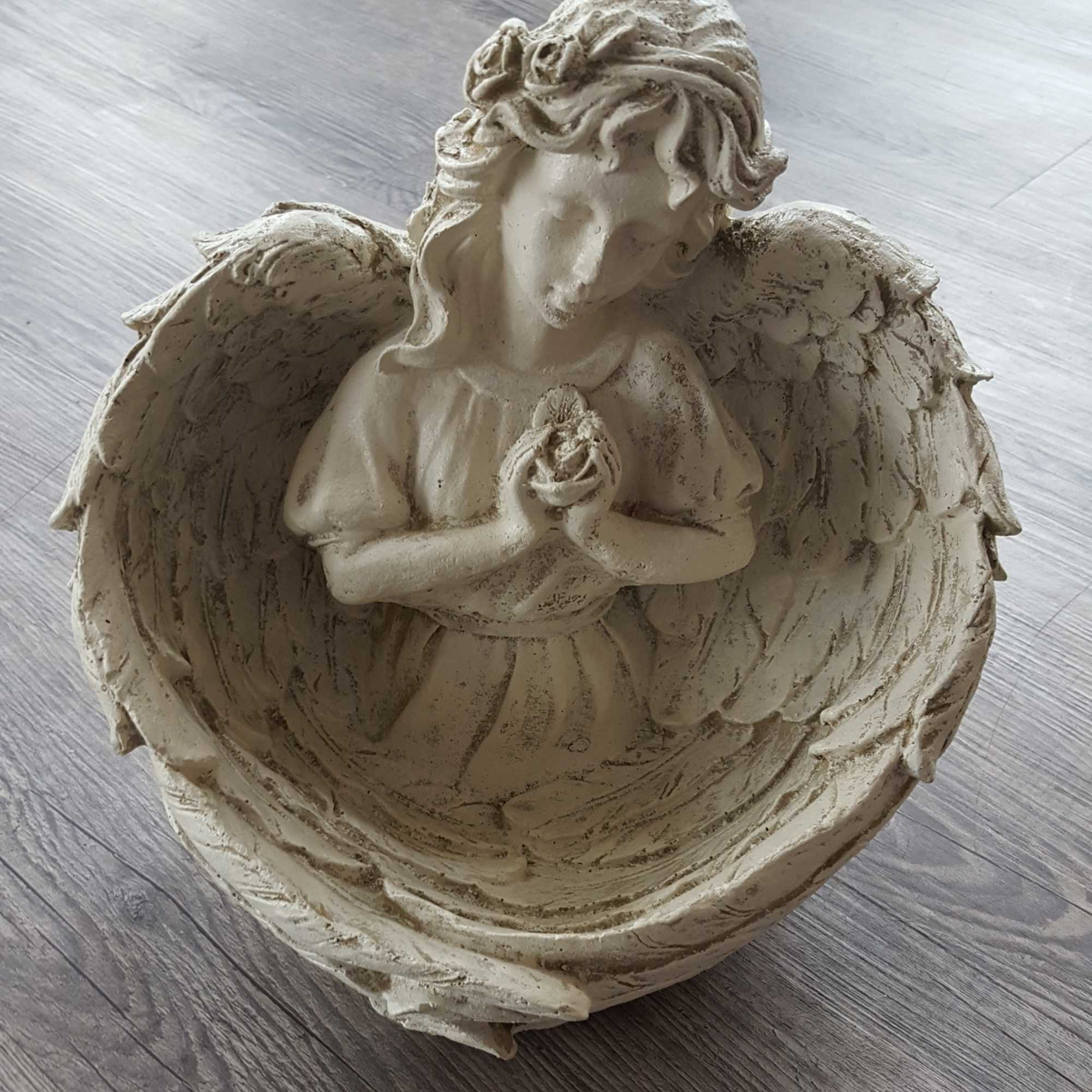 Angel figurine holding a flower inside a shell-shaped bowl