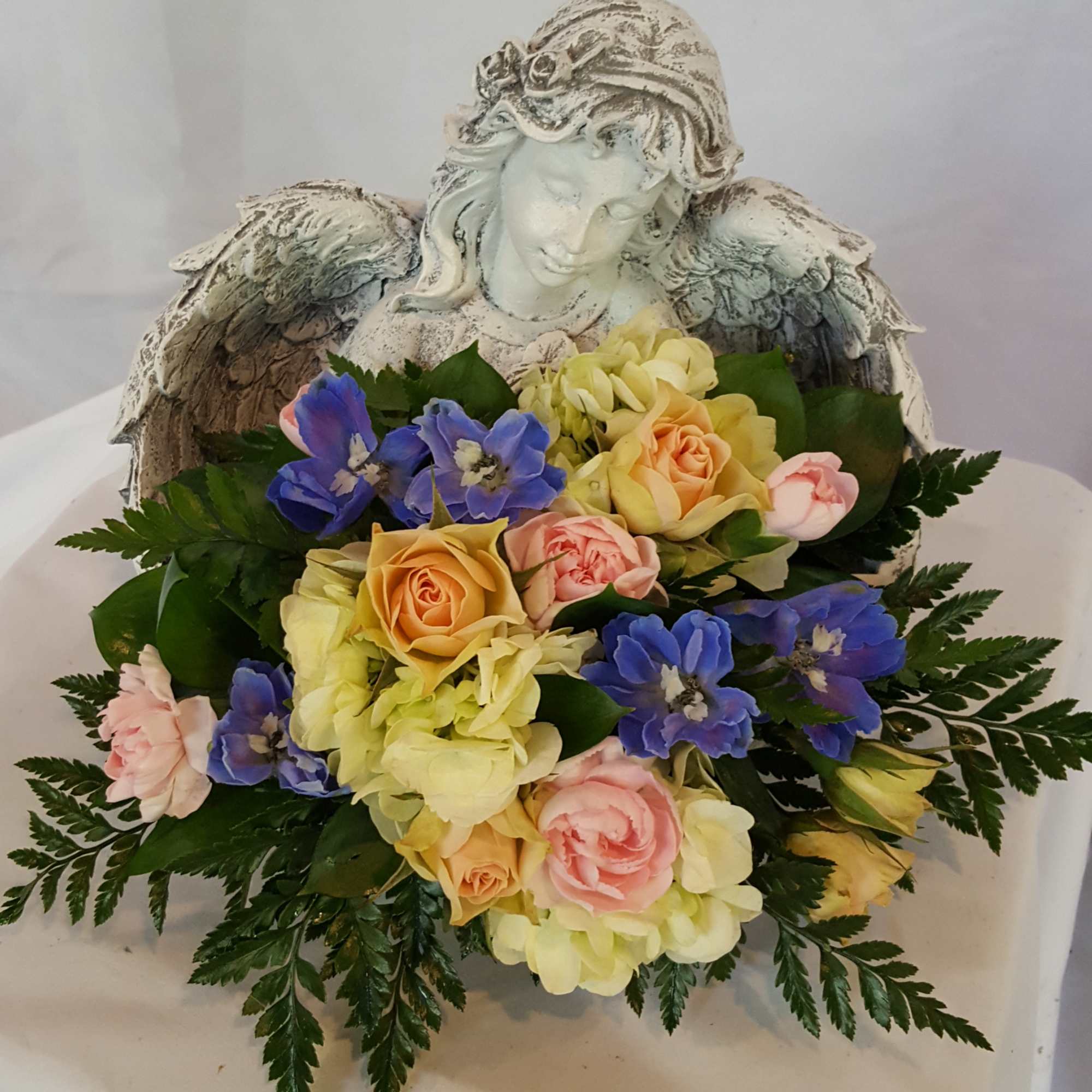 A beautiful, concrete angel holding a fresh bouquet of flowers. This thoughtful