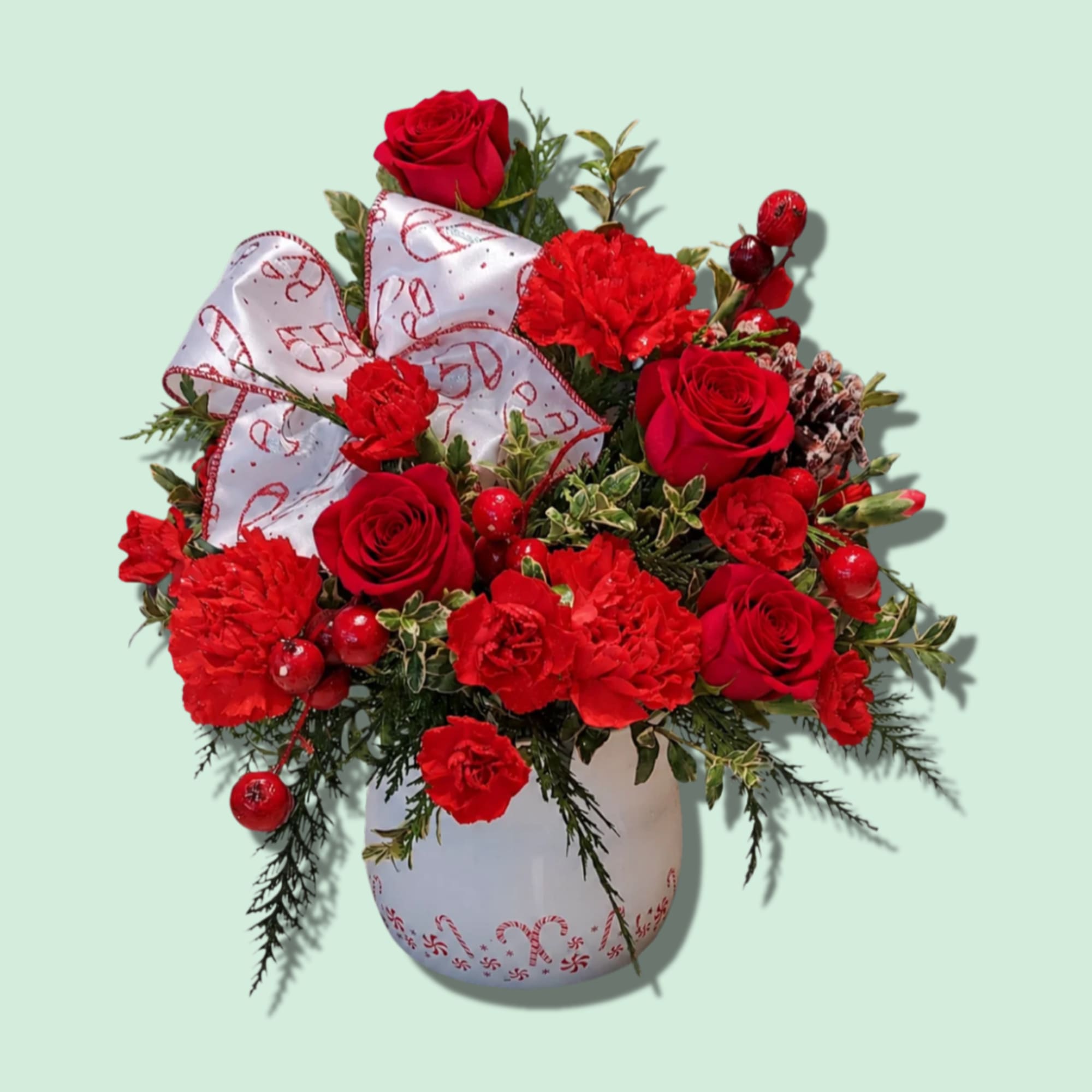 Red roses and carnations in a white vase with a decorative bow