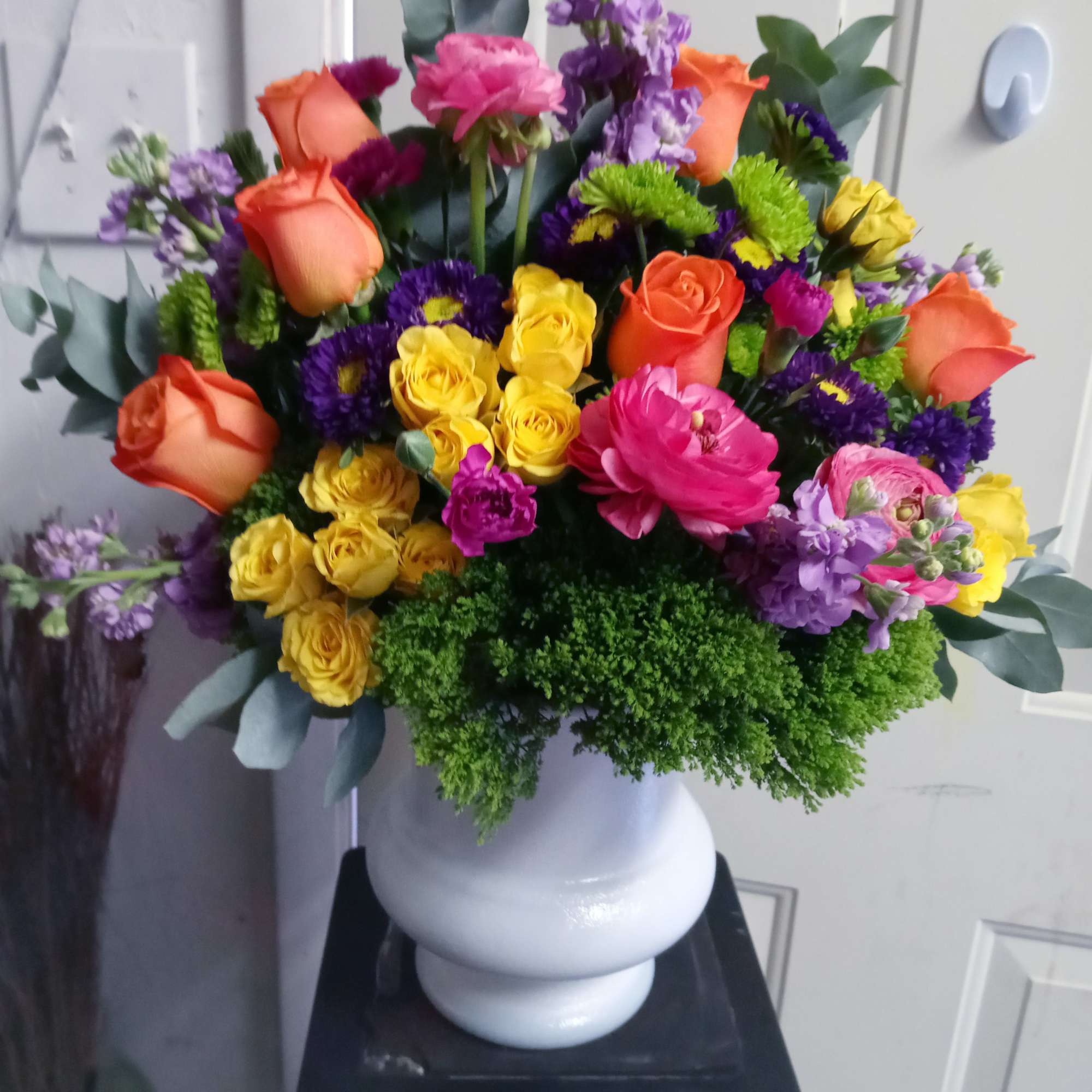 Colorful bouquet of roses and mixed blooms in a white vase