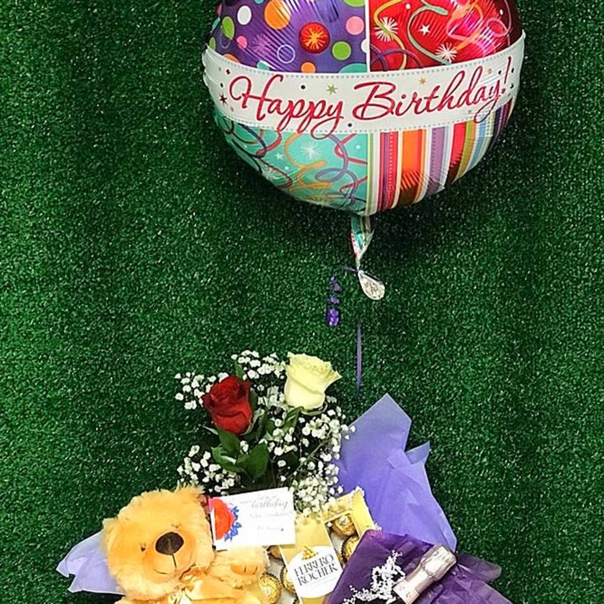 Birthday gift basket with roses, teddy bear, chocolates, wine bottle, and a Happy Birthday balloon