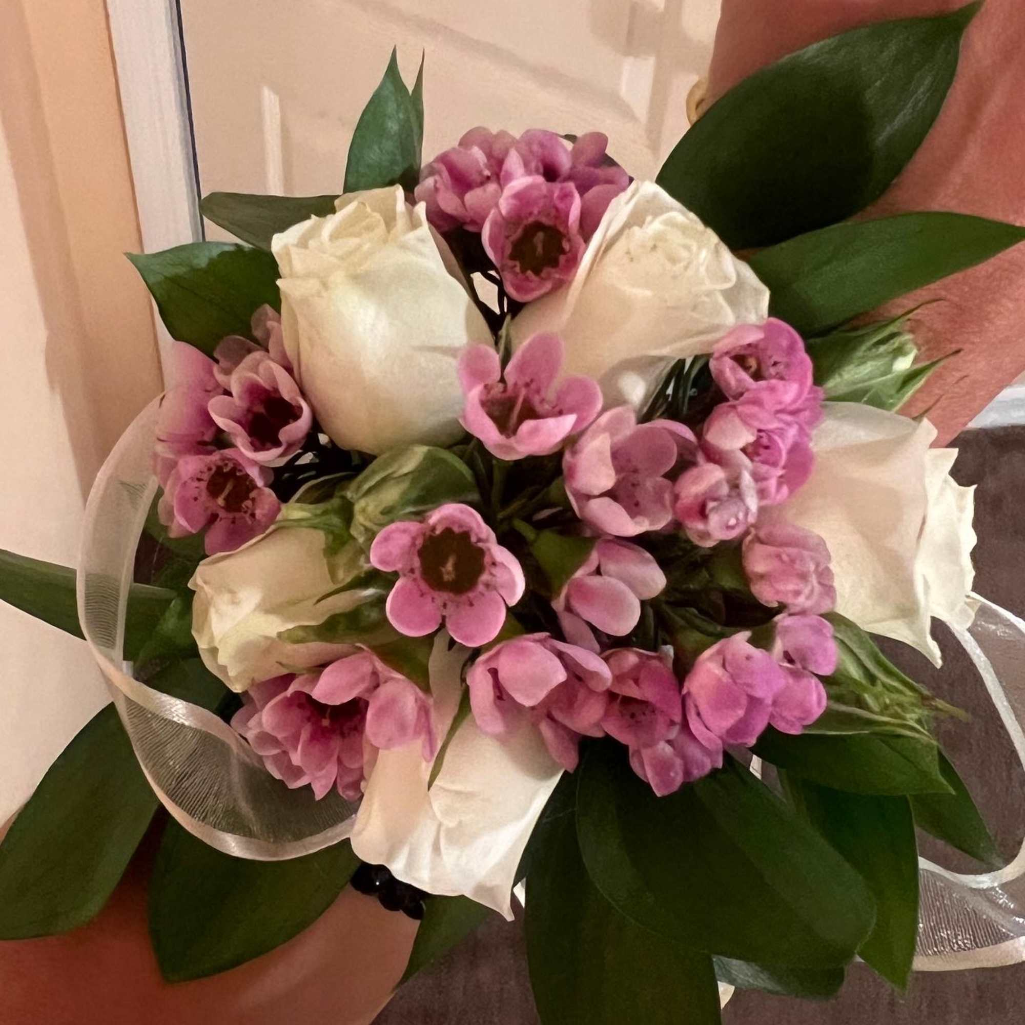 Small hand-tied bouquet of white roses and pink blossoms with a white ribbon accent