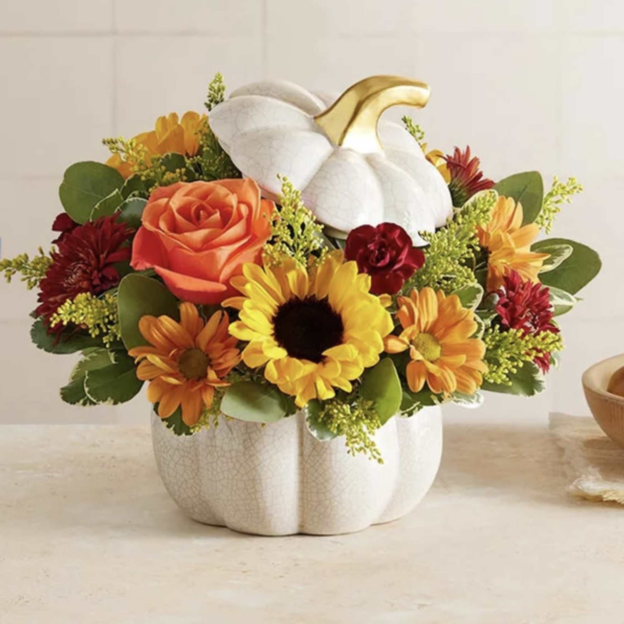 Fall arrangement with sunflowers, orange rose and mums in a white ceramic pumpkin container