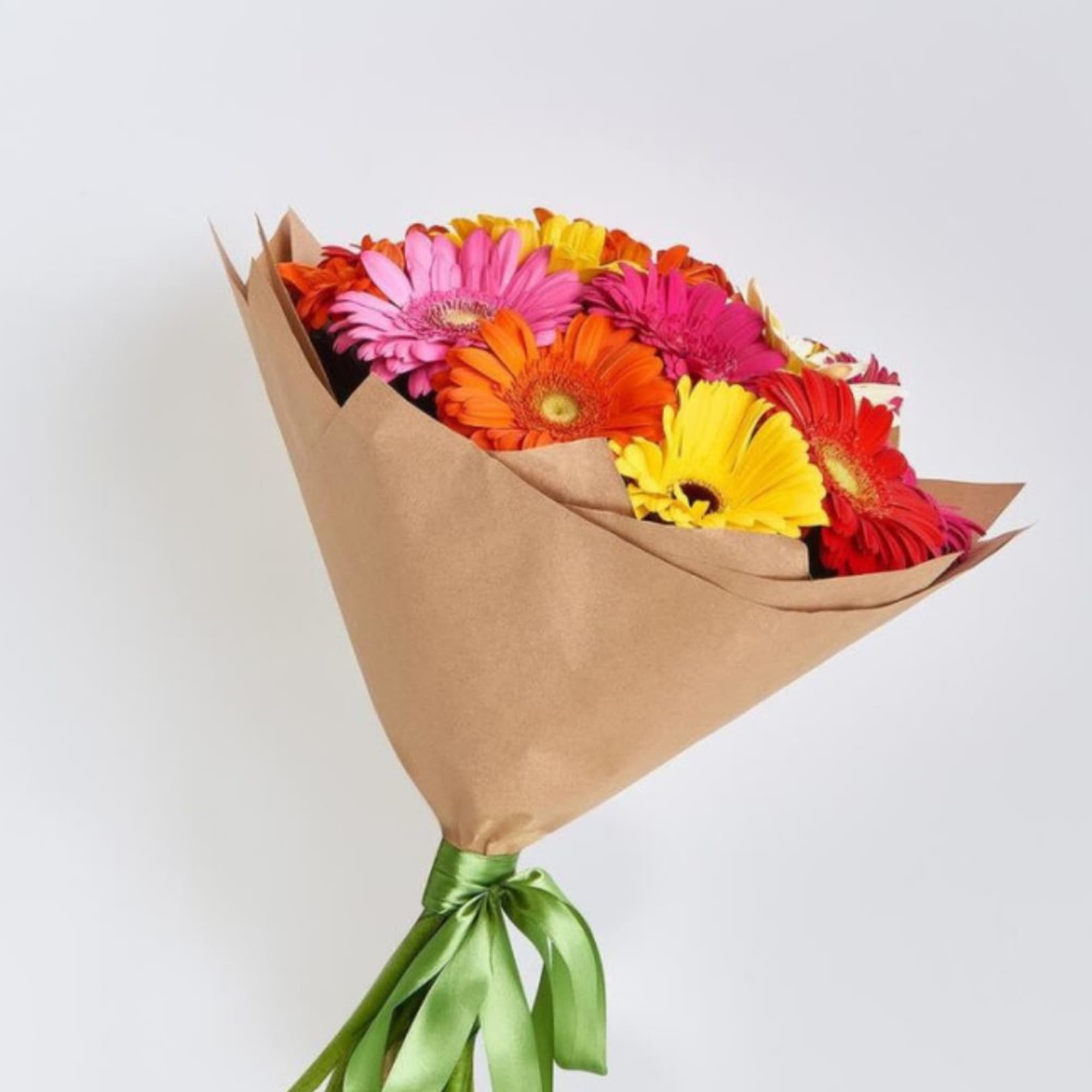 Bouquet of bright gerbera daisies in kraft paper wrap tied with a green ribbon