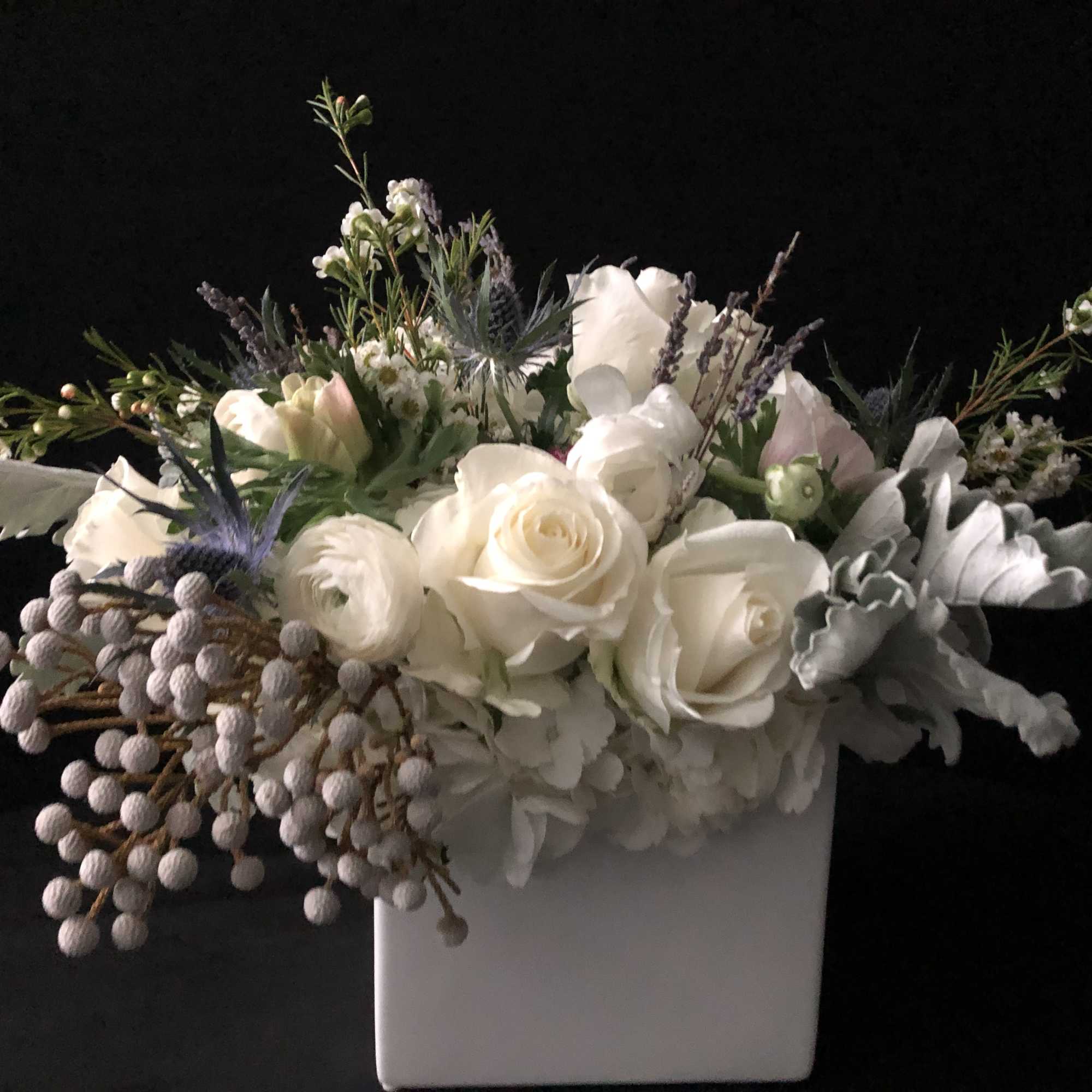 White floral arrangement in a square vase with lavender accents
