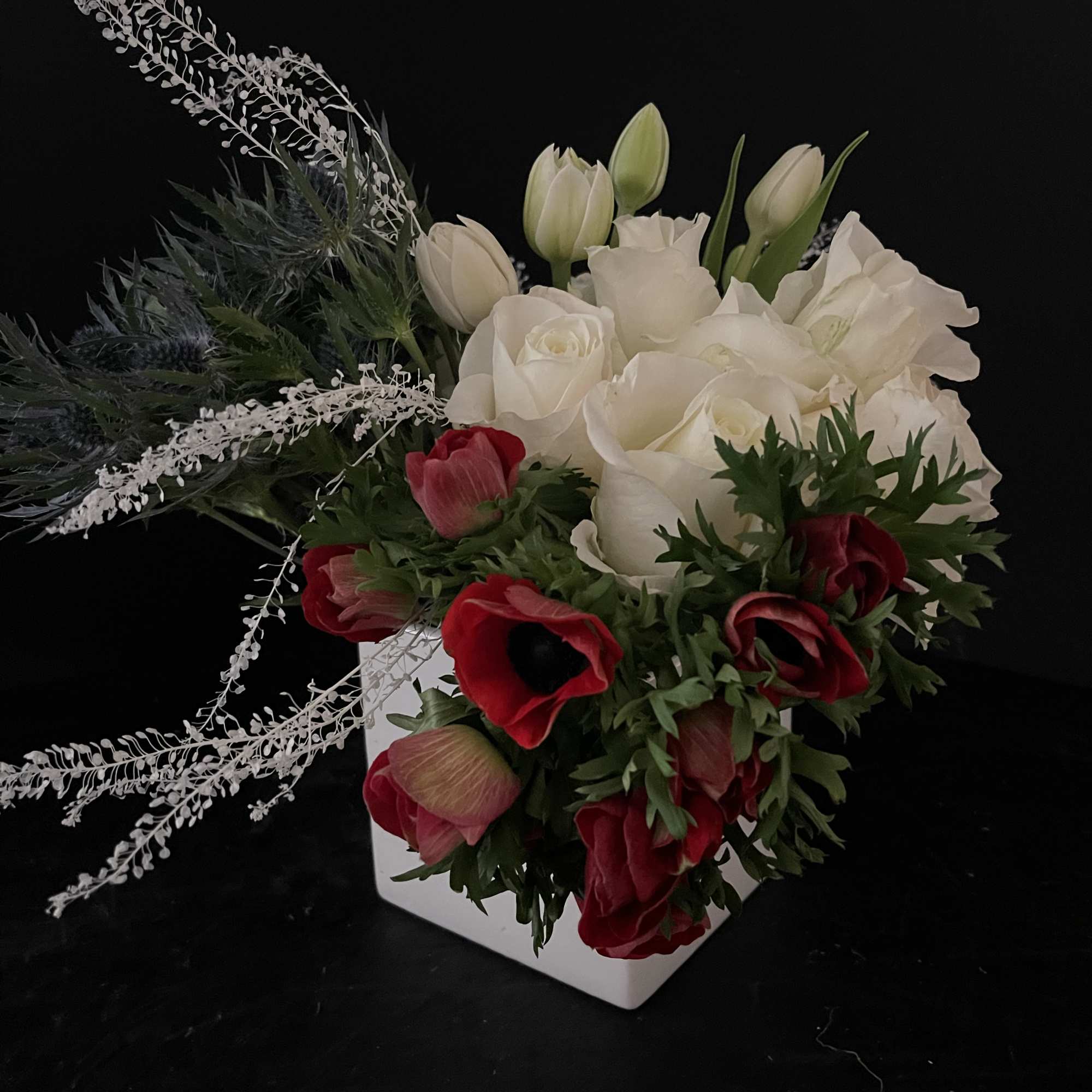 White and red floral arrangement in a white square vase
