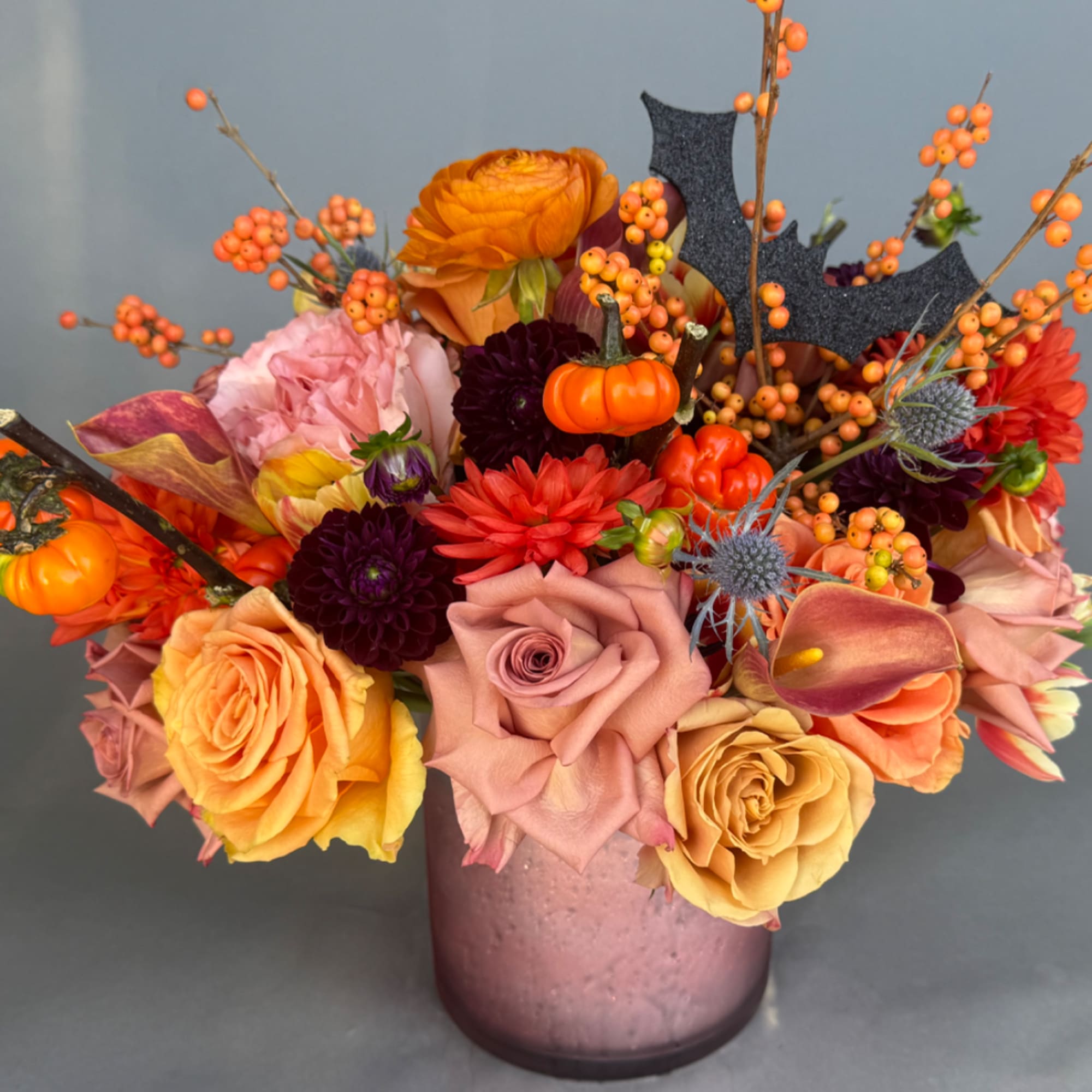 Autumn bouquet of roses, dahlias, and berries in a pink vase