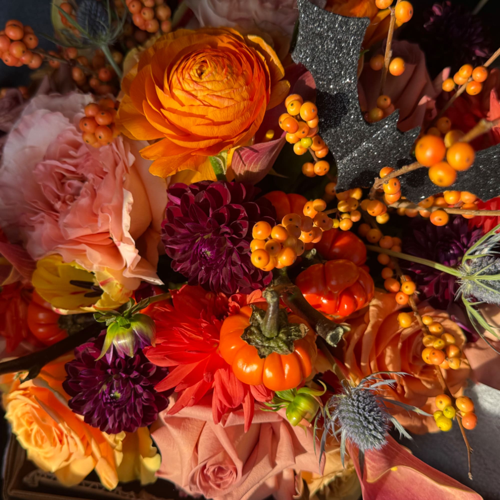 Autumn bouquet with orange, pink, and purple flowers and small pumpkins